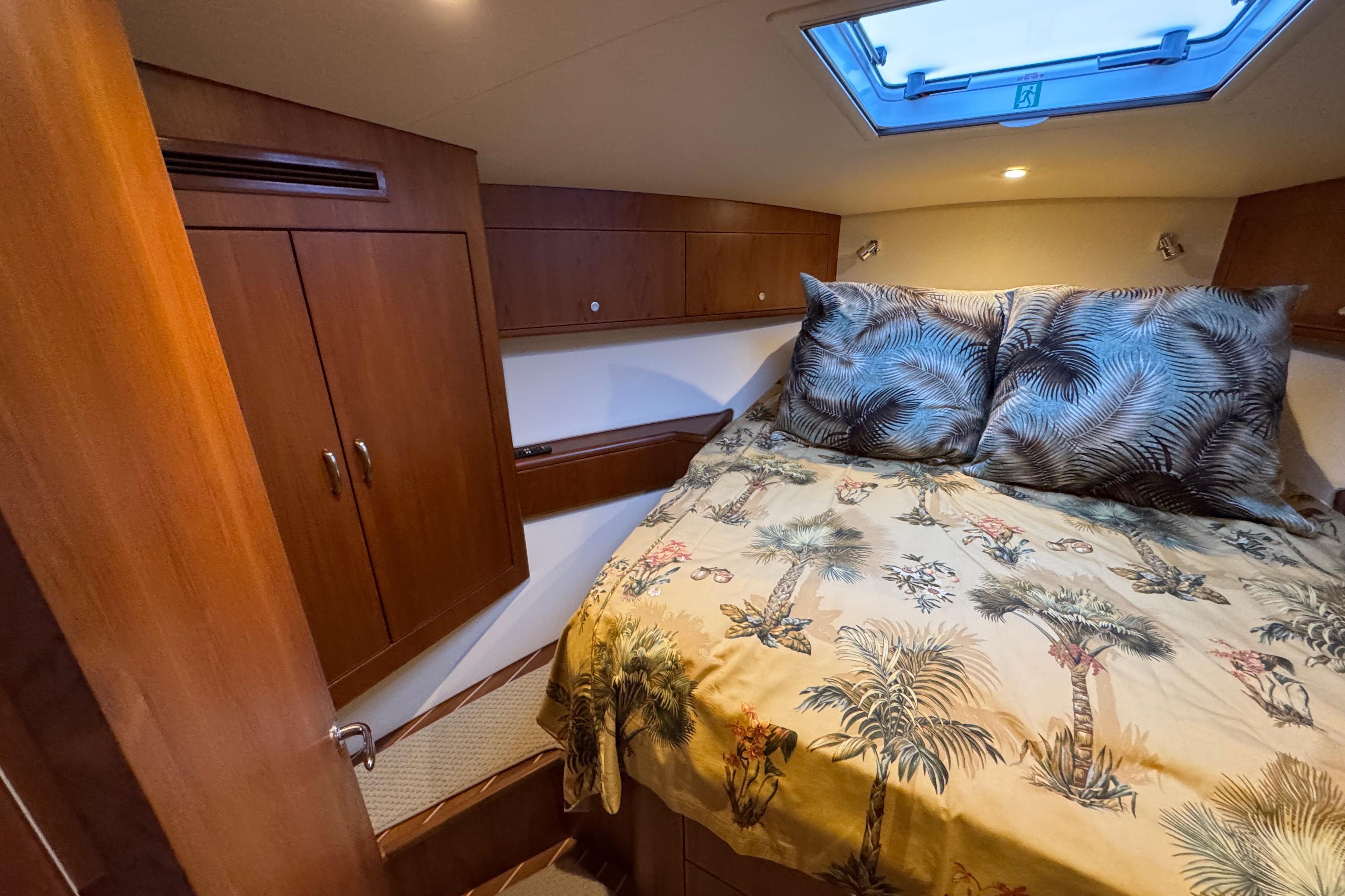 2013 Cabo 44 Hardtop Express cabin with tropical bedding and wooden cabinetry.
