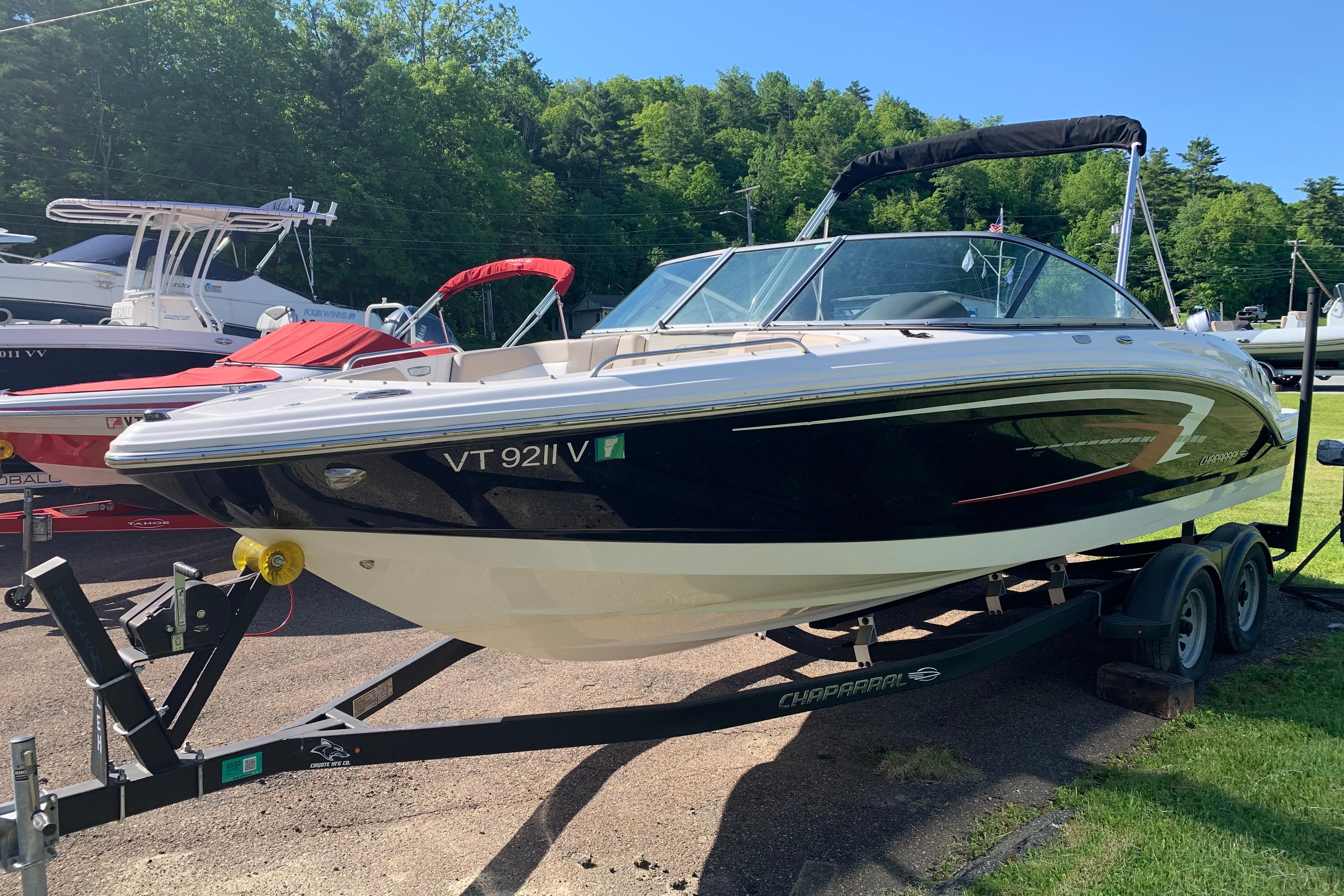 2022 Chaparral 23 SSi boat on trailer, parked outdoors with lush green background.