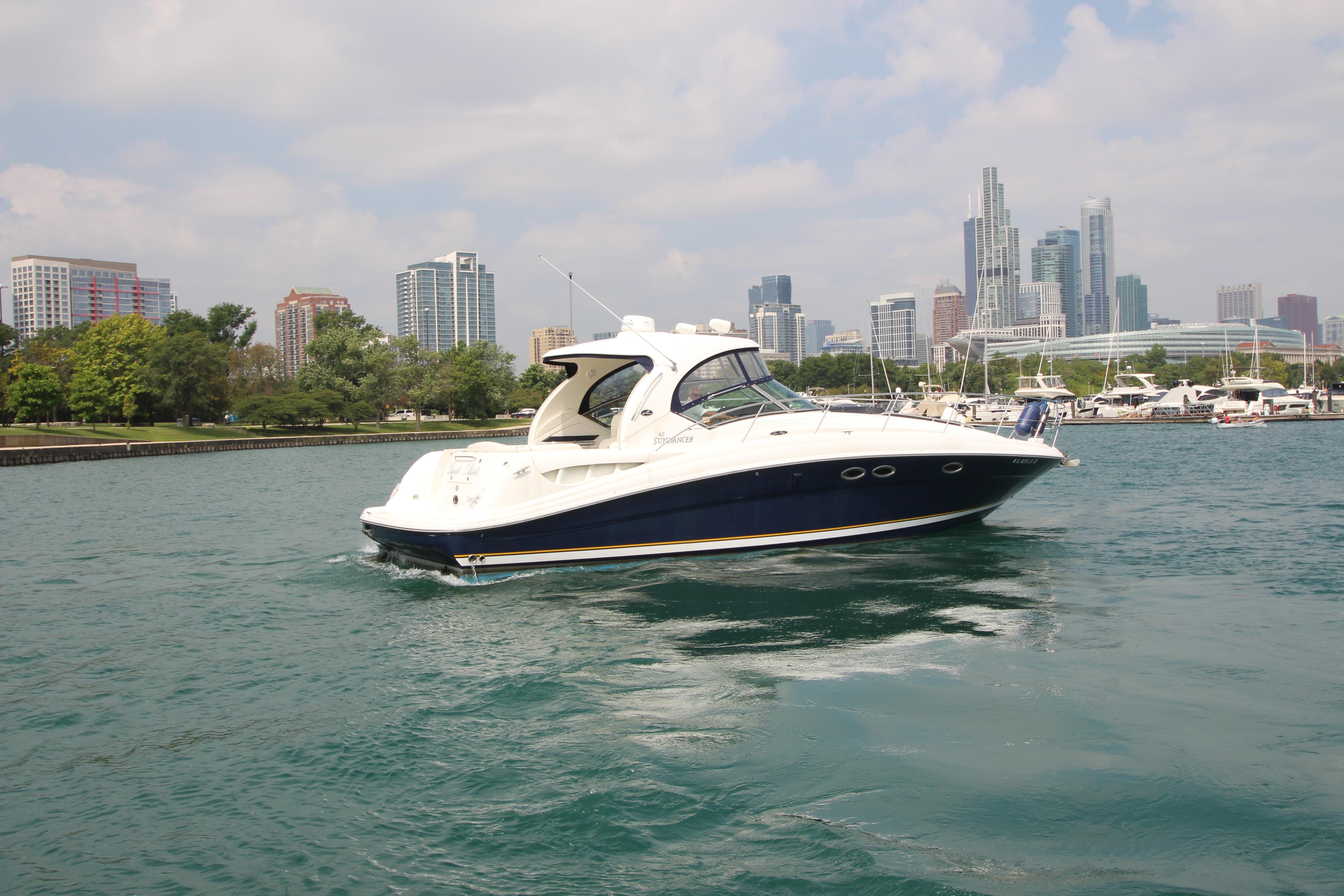 2004 Sea Ray 40 Sundancer yacht cruising near city skyline and marina.
