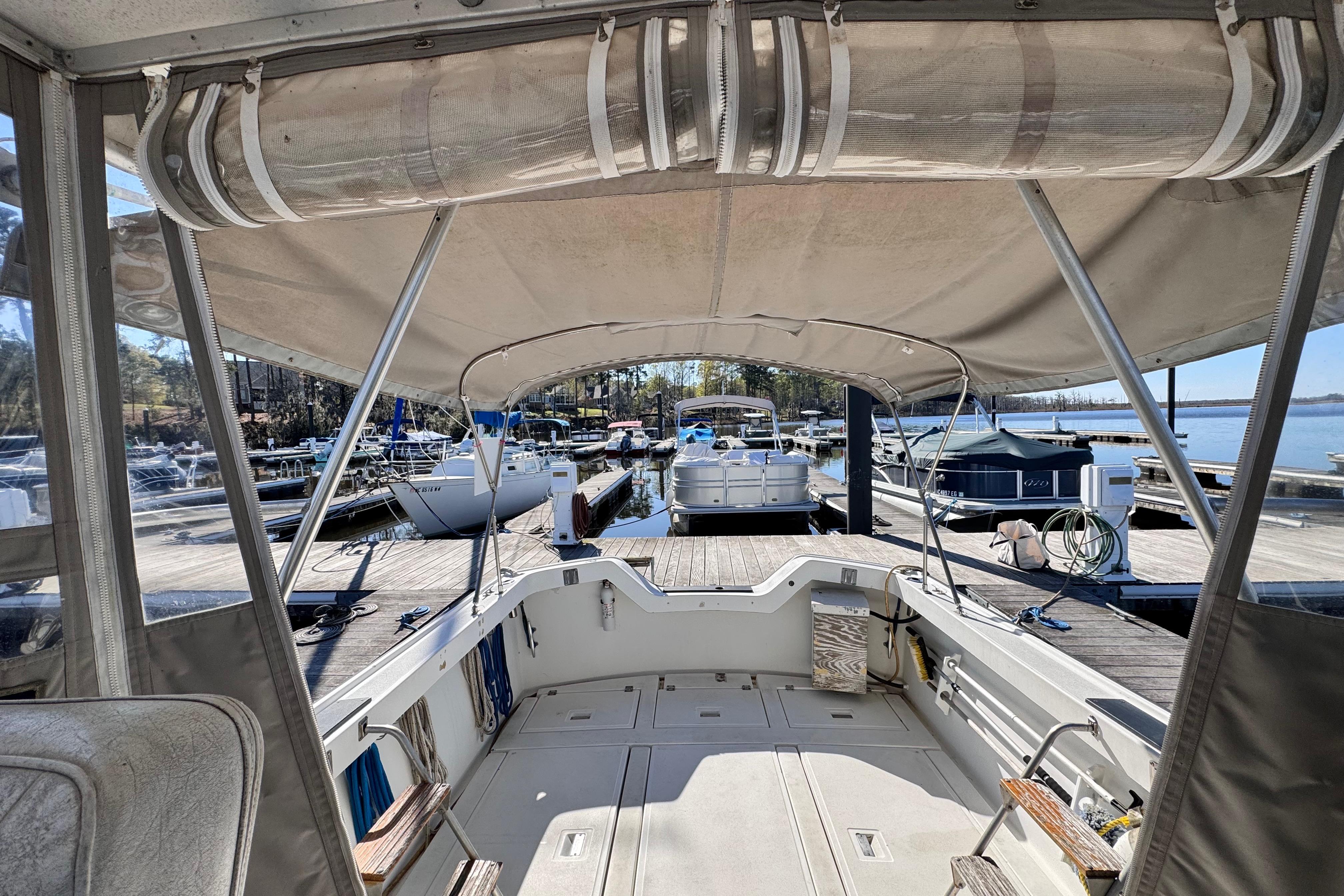 1987 Luhrs Alura 30 boat docked at a marina, featuring a spacious cockpit and canopy.