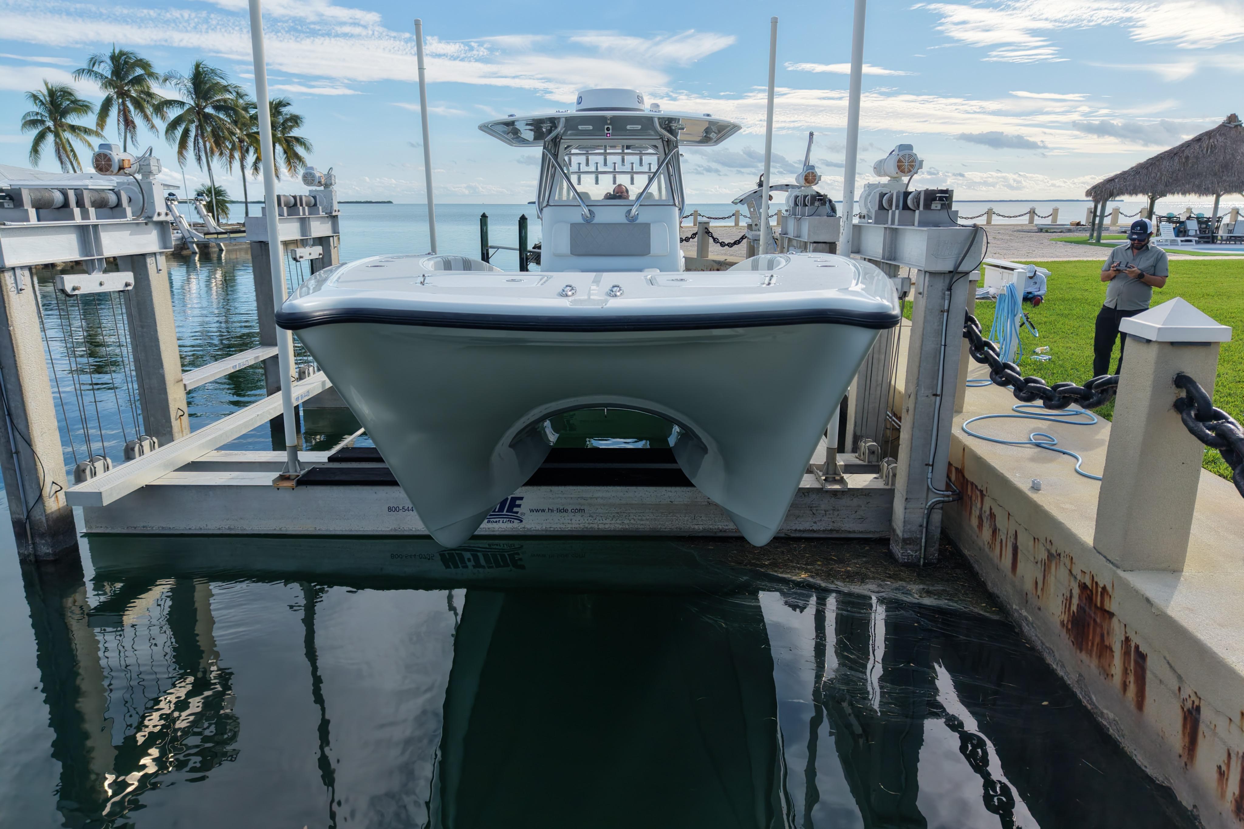 2022 Freeman 34VH boat on lift by tropical waterfront with palm trees.