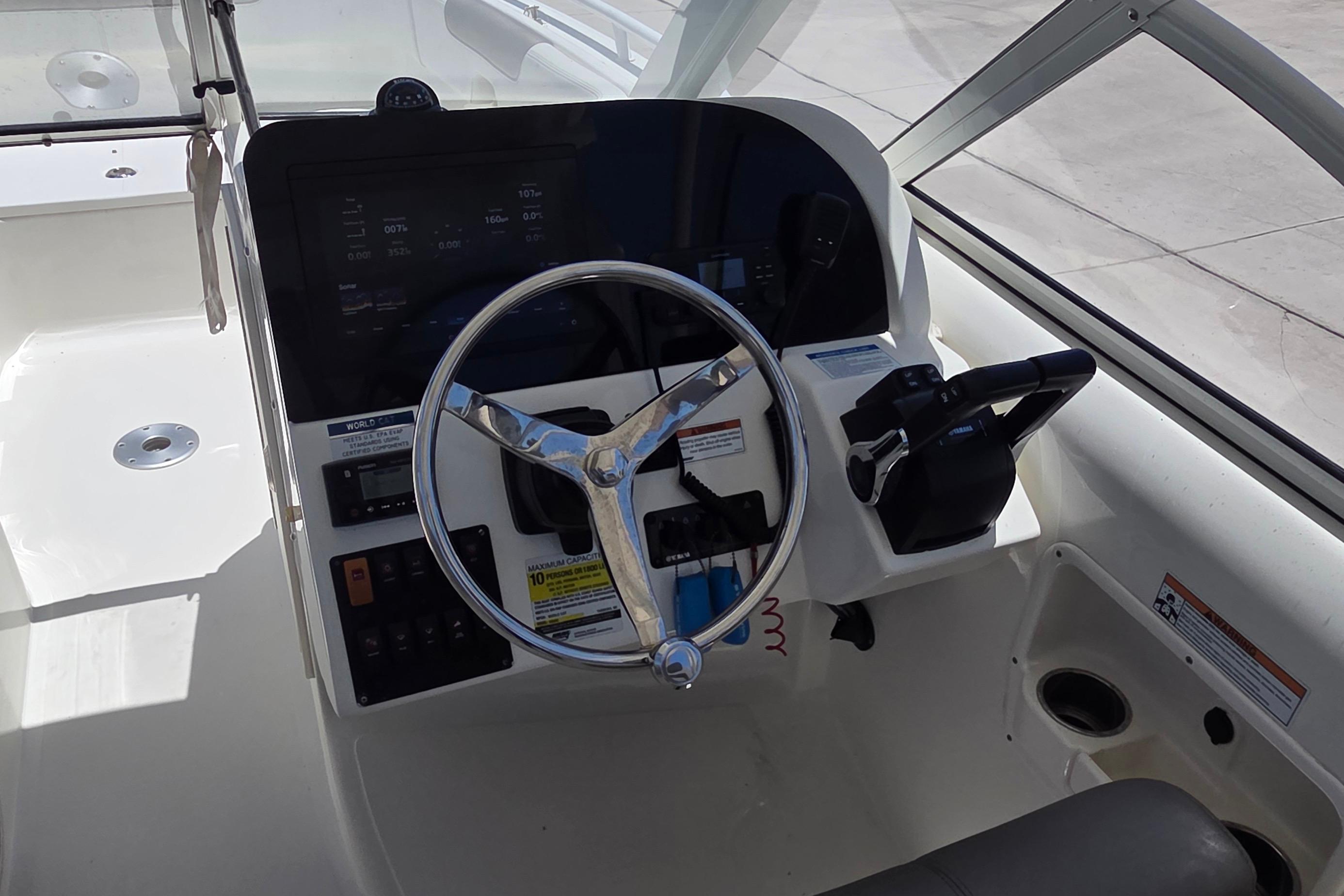 2022 World Cat 255 DC boat helm with steering wheel and control panel.