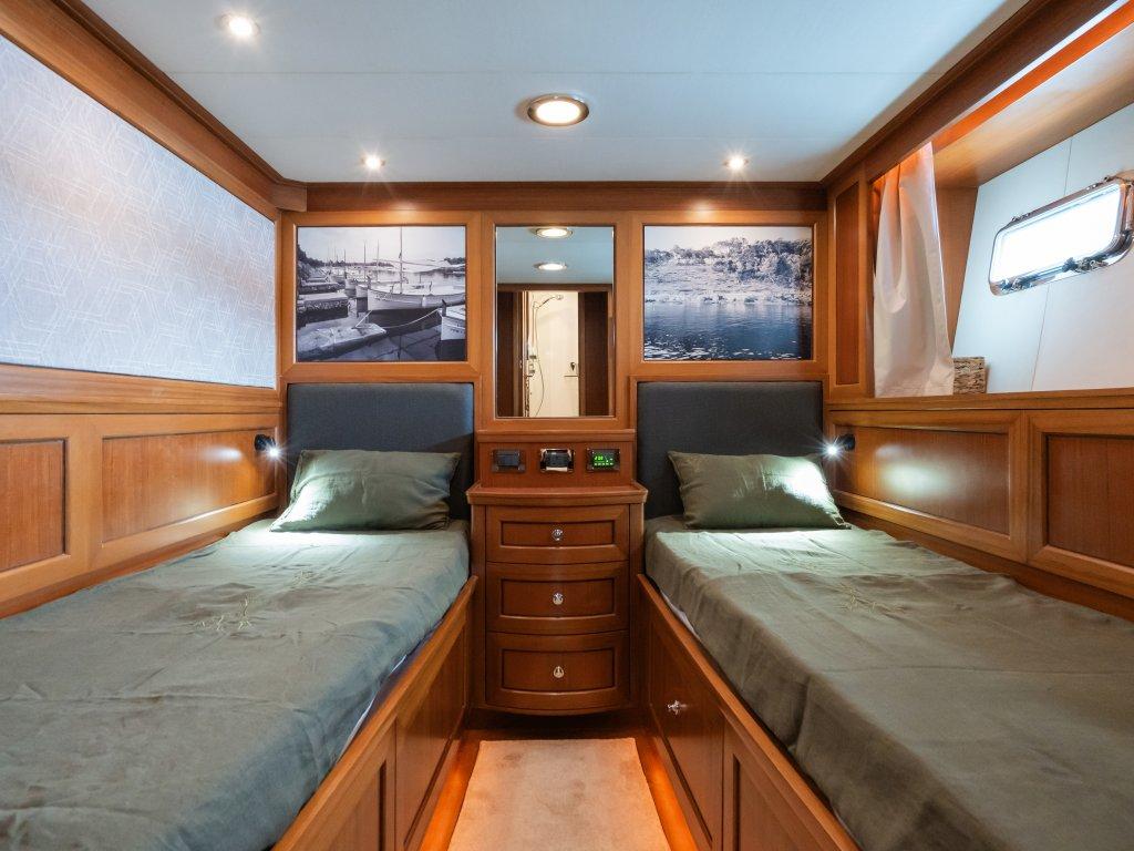 Luxurious cabin interior of 2008 Trader 64 Sunliner yacht with twin beds and elegant wood finish.