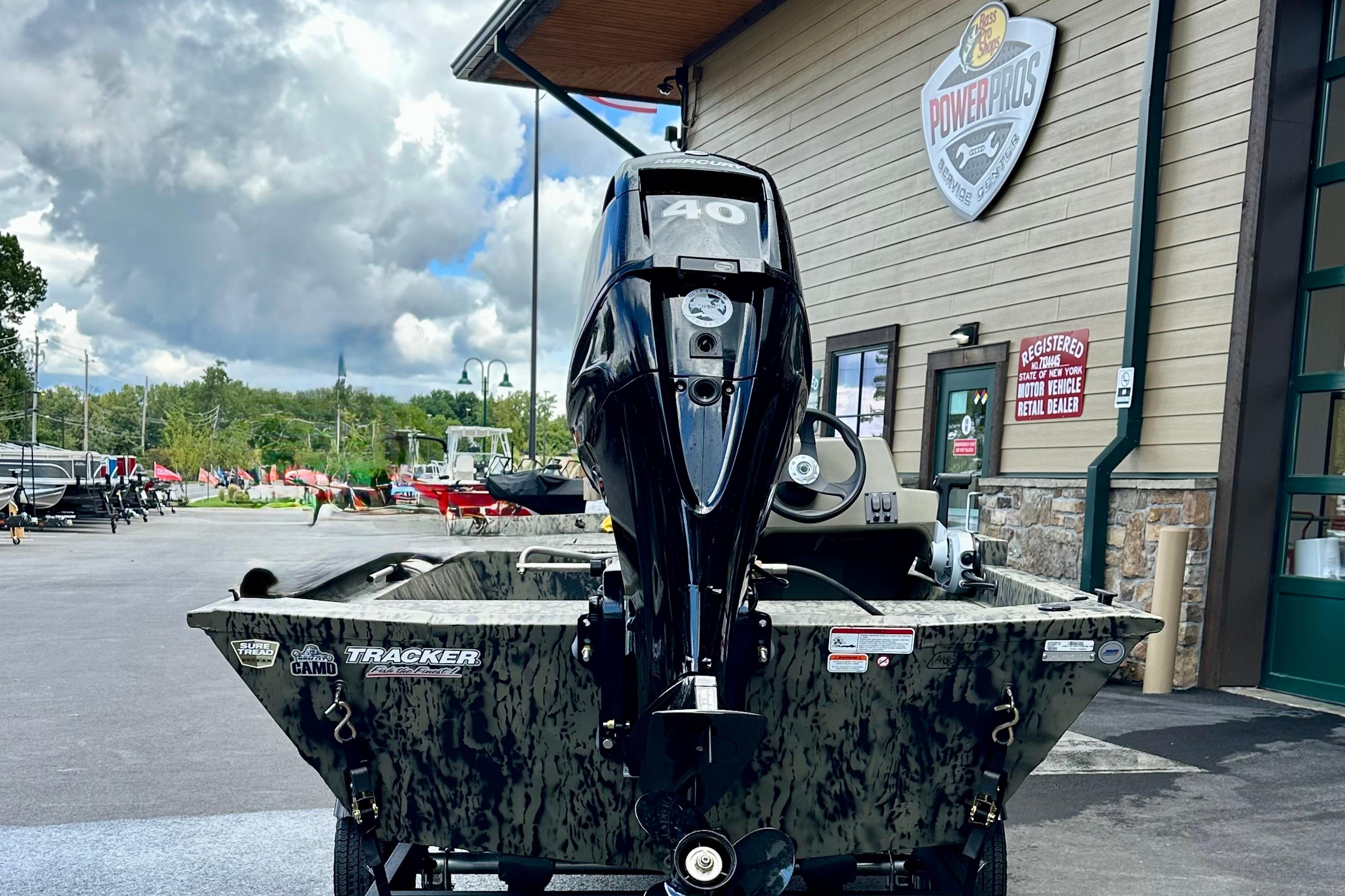 2026 Tracker Grizzly 1648 SC boat with motor, parked outside dealership.