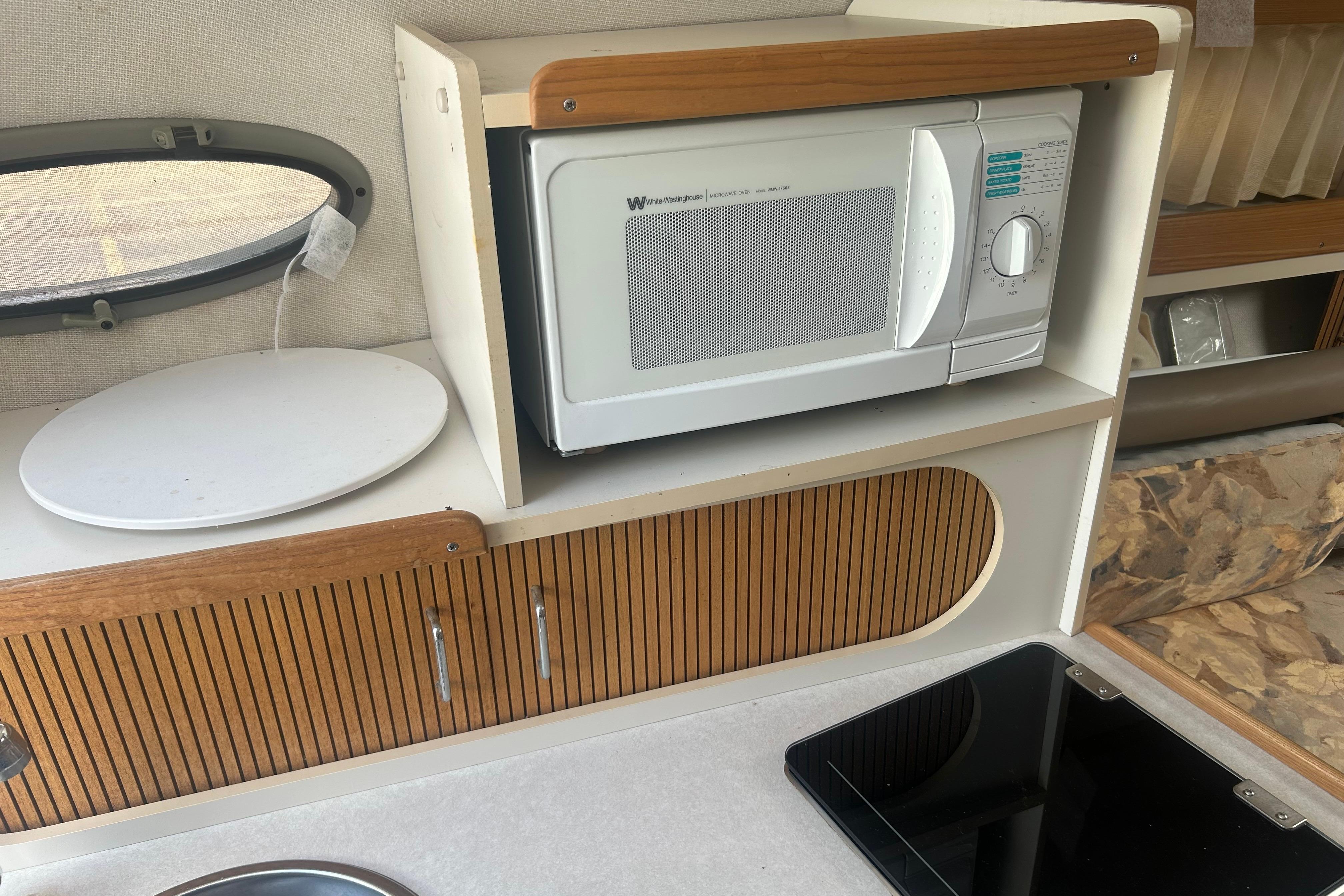 1998 Four Winns 258 Vista interior with microwave, wooden cabinets, and countertop.