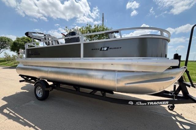 2026 Sun Tracker Bass Buggy 18 DLX pontoon boat on trailer under a sunny sky.