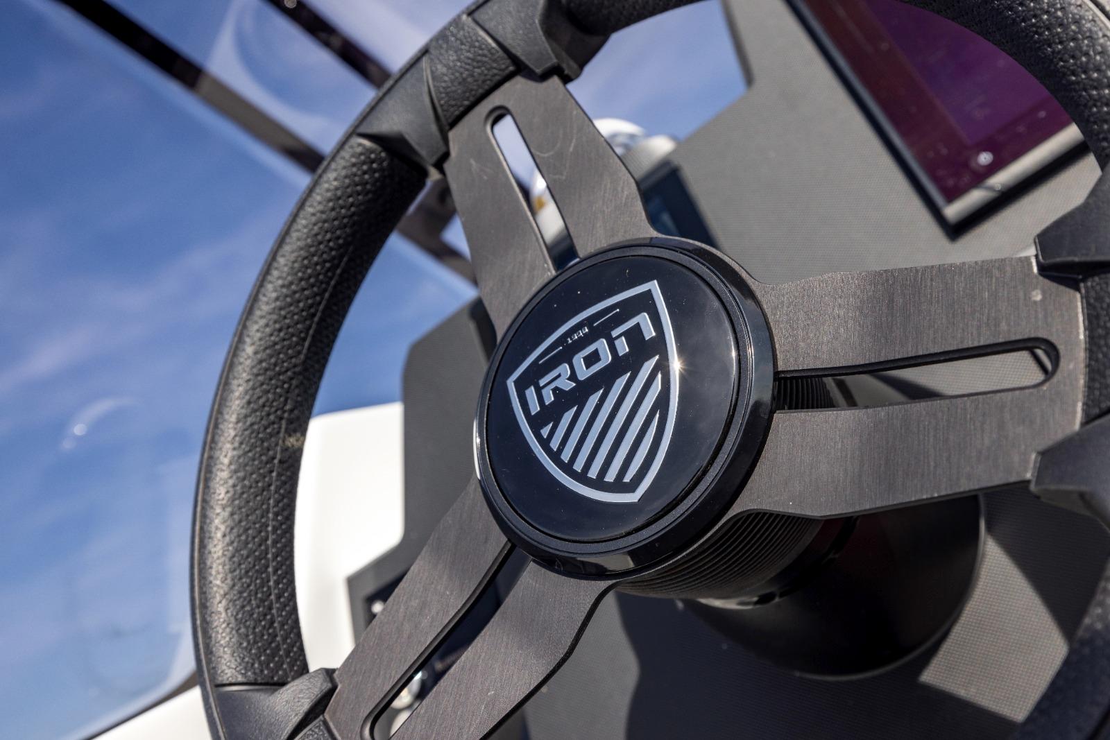 Steering wheel of 2022 Iron 707 boat, featuring sleek design and logo.