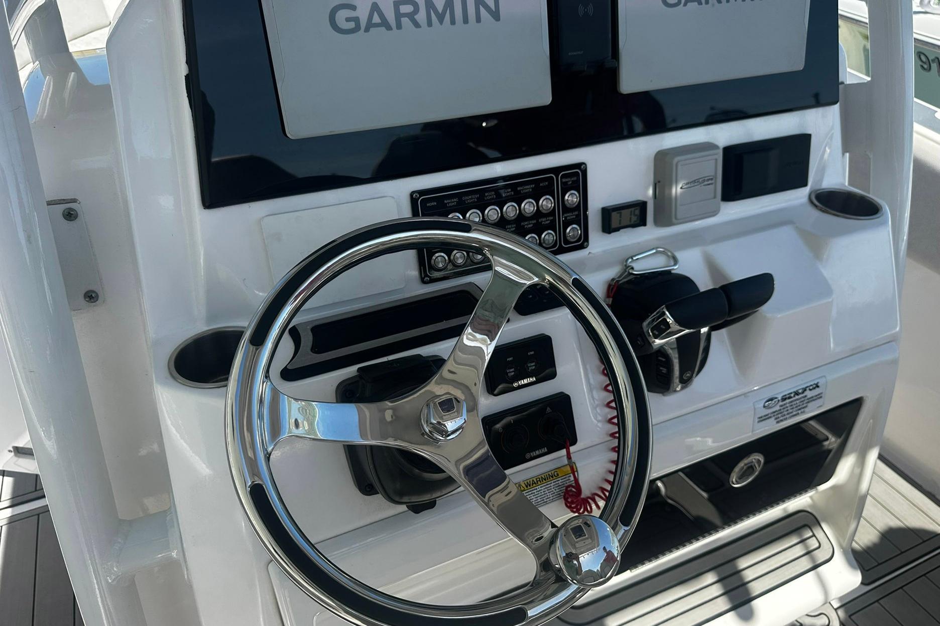 Steering console of a 2002 Sea Fox 228 Commander boat with Garmin displays.