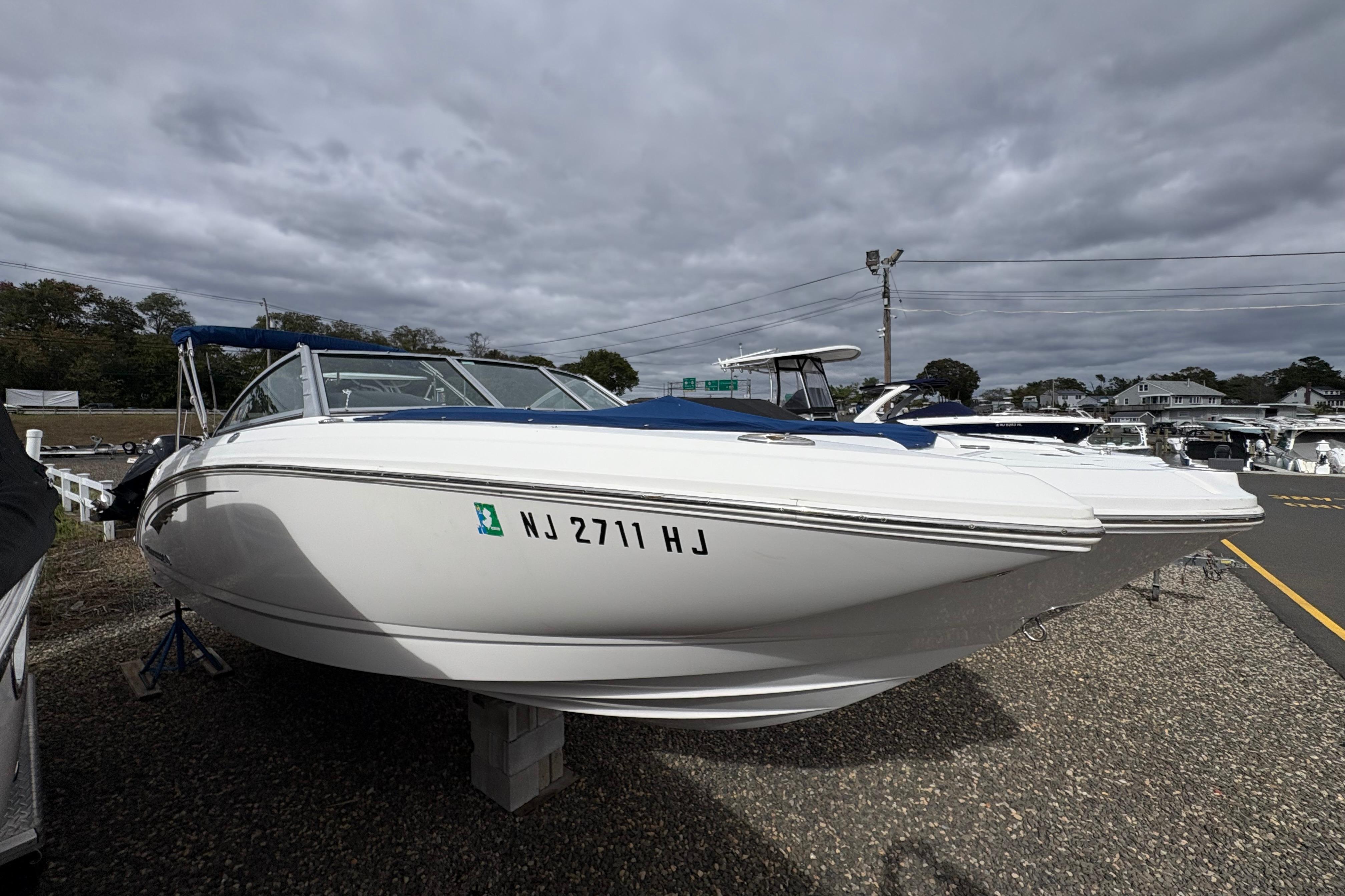 2015 Chaparral 264 Sunesta boat on display, parked on gravel under cloudy skies.