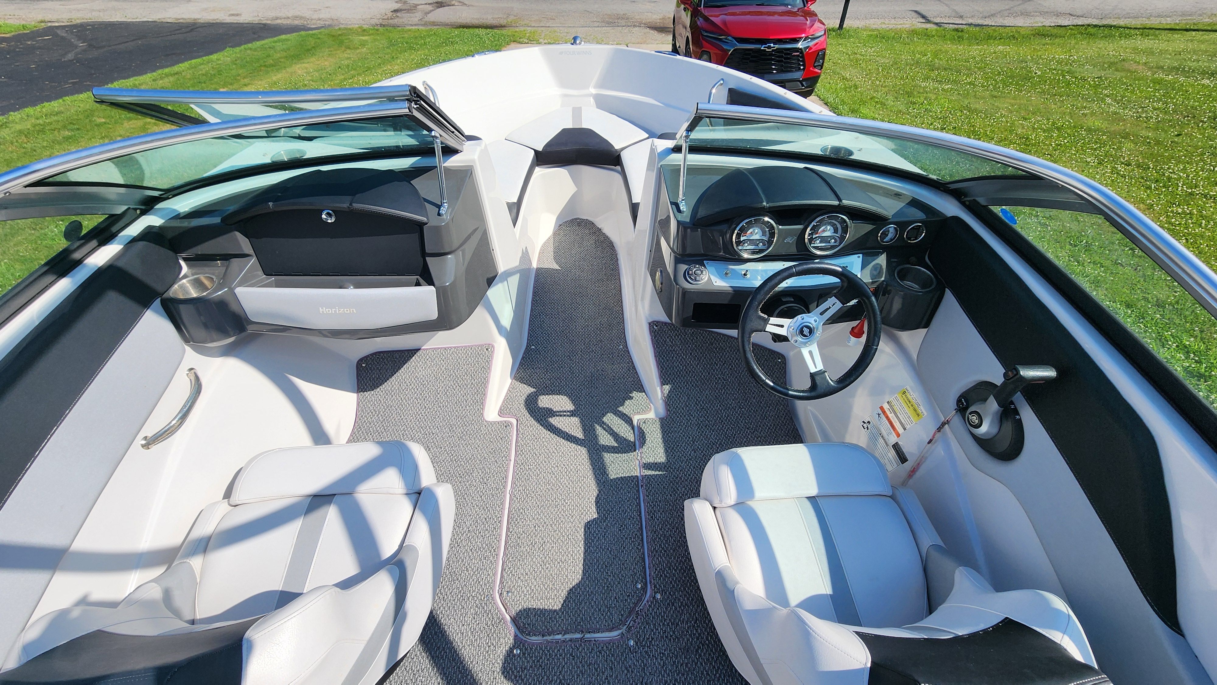 The image shows the cockpit of a 2015 Four Winns H190 boat with white seats and dashboard.