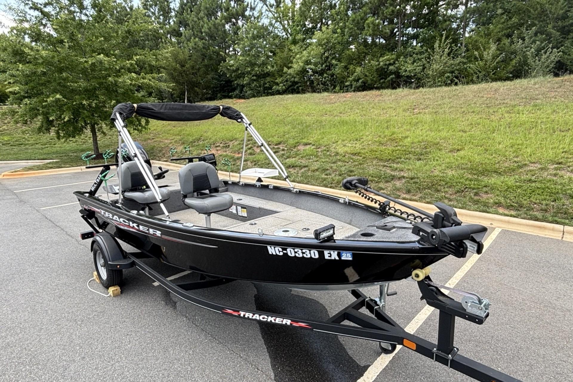 2022 Tracker Super Guide V-16 T fishing boat on trailer in parking lot.
