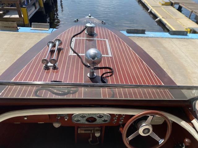 Classic 2000 Grand Craft Runabout with wooden deck and vintage steering wheel at dockside.