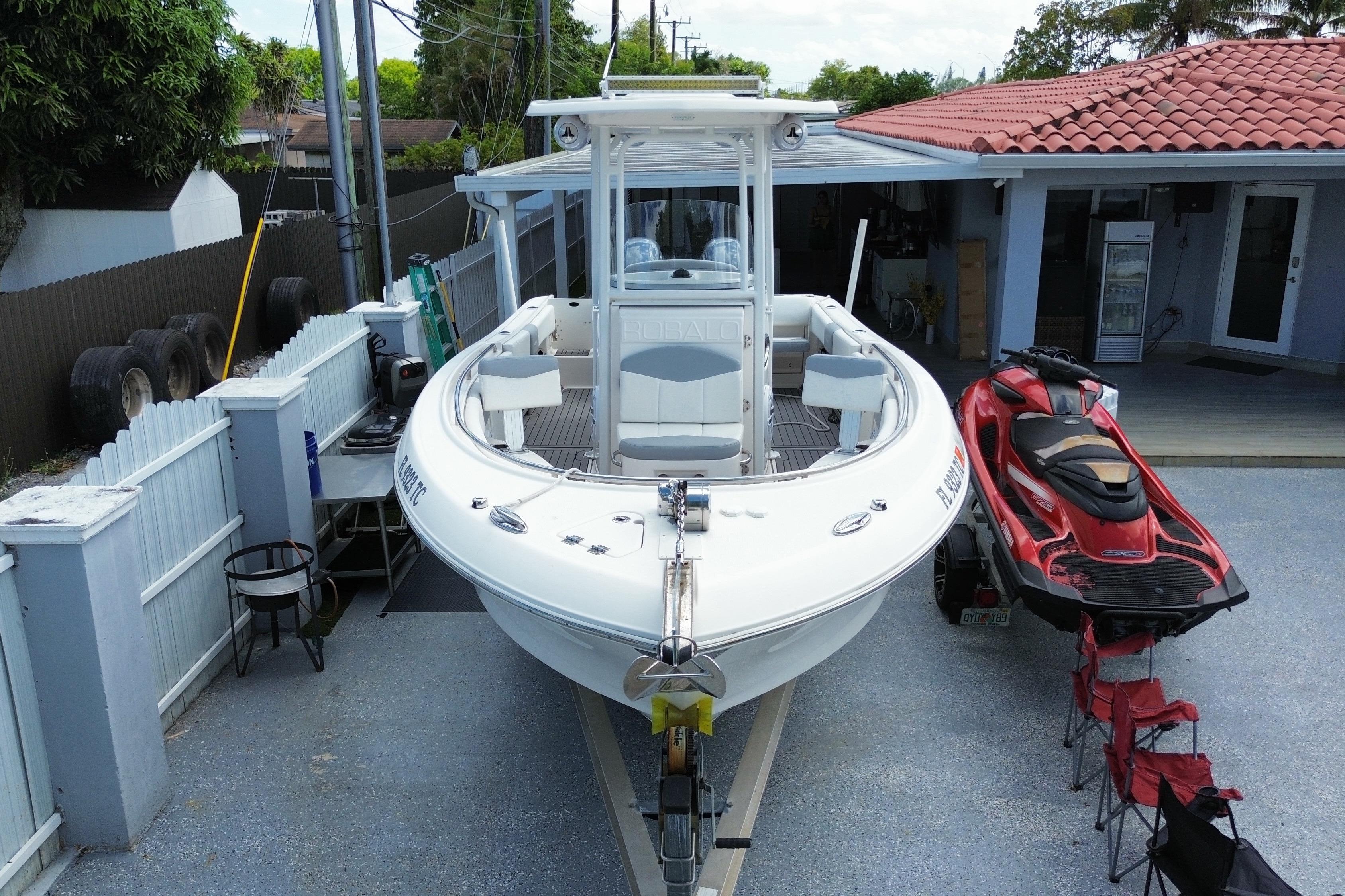 2022 Robalo R242 Center Console boat parked beside a red jet ski.
