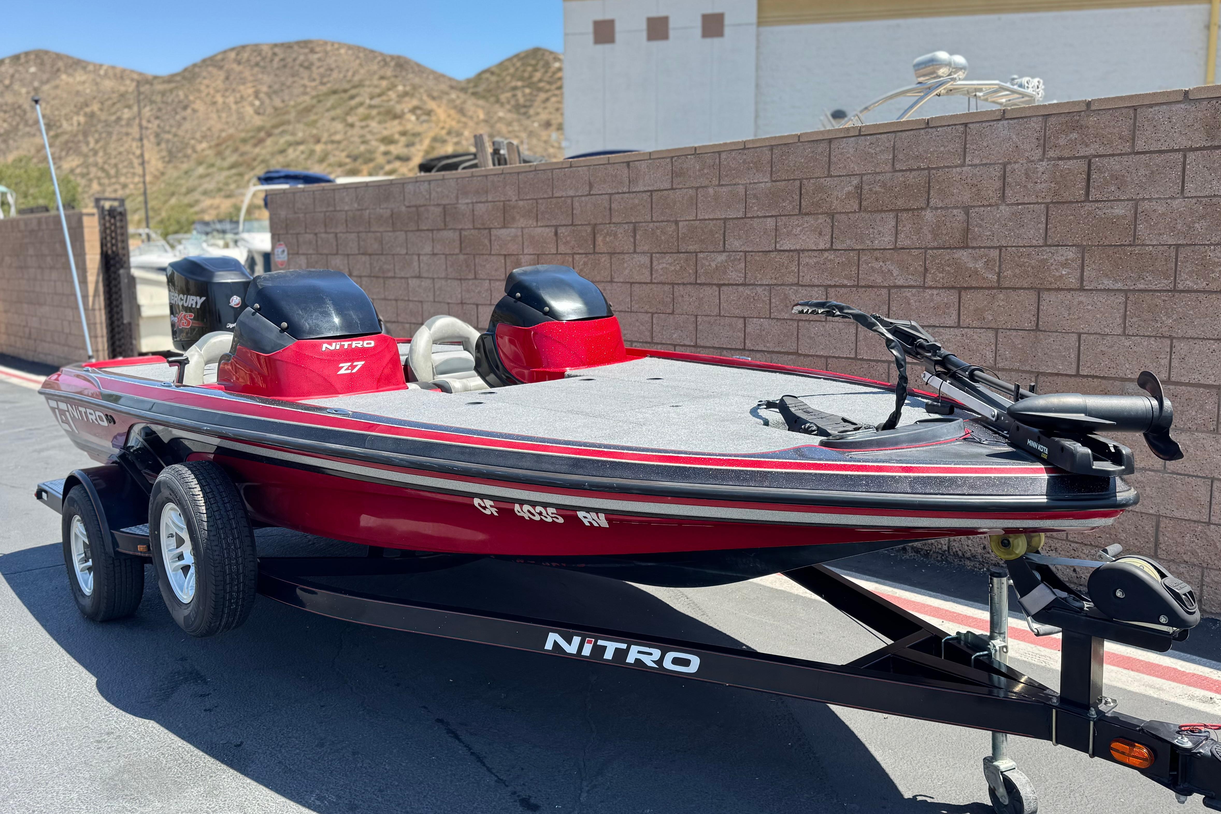 Red 2012 Nitro Z-7 boat on trailer, parked outdoors near brick wall.
