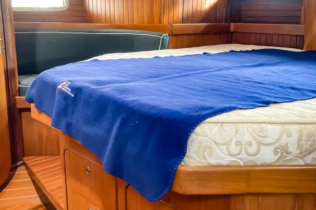 Cozy cabin interior of 1999 Hylas 54 yacht with blue blanket on bed.