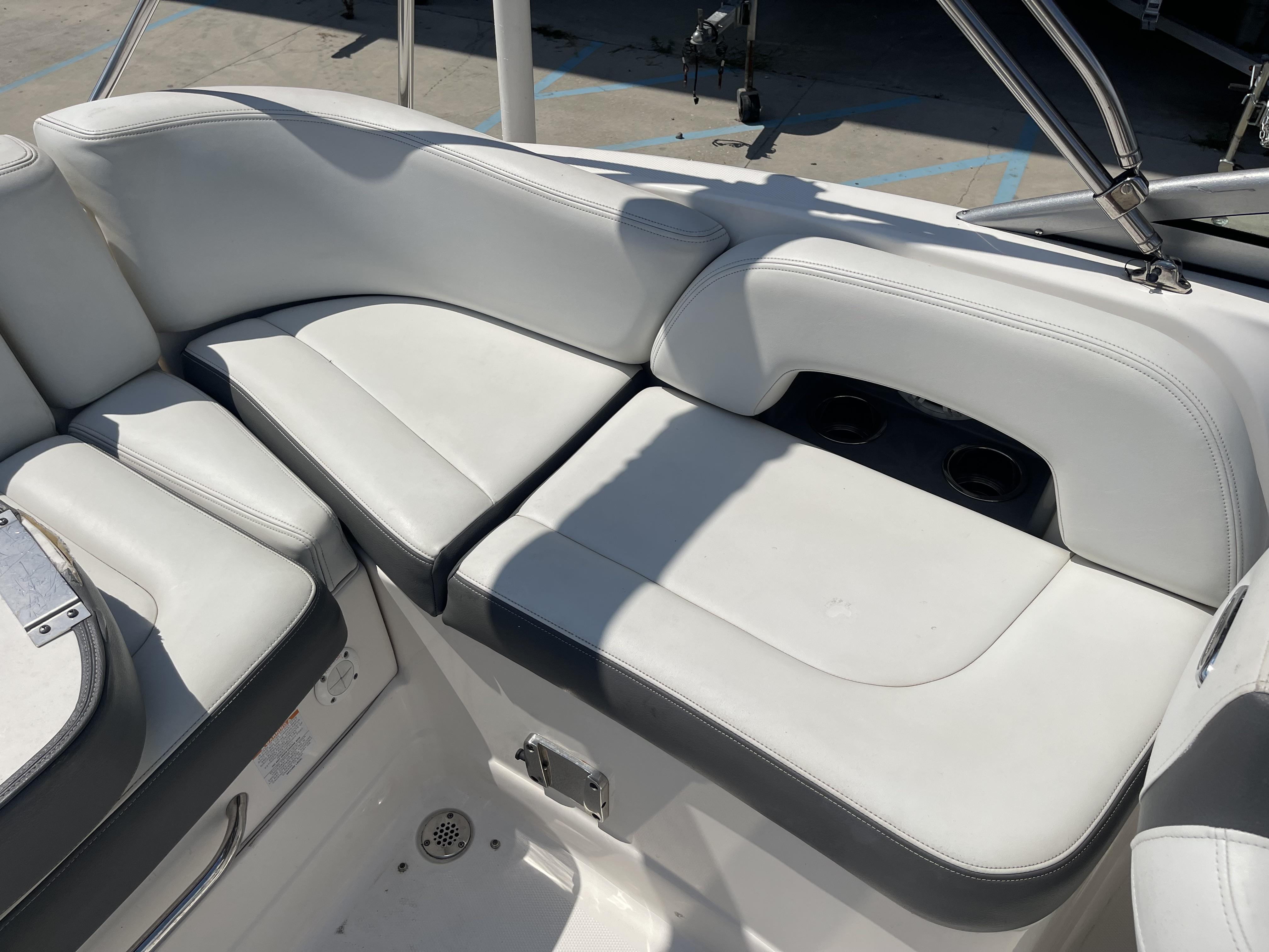 2014 Chaparral Sunesta 224 boat interior with white cushioned seating and cup holders.