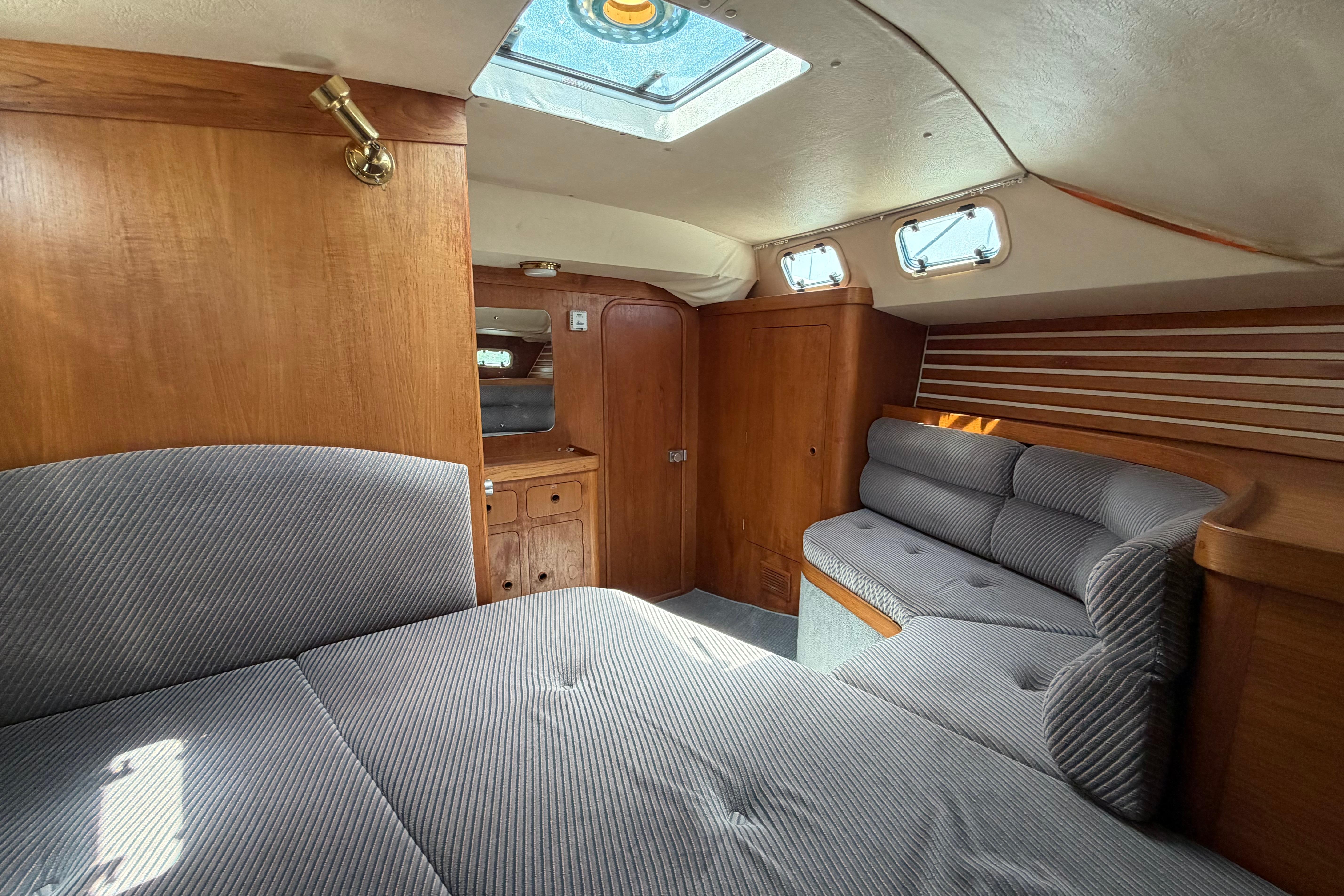 Cozy interior of 1987 Moody 376 sailboat with wood paneling and cushioned seating.
