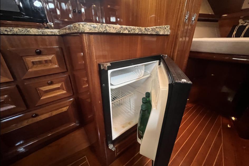 Open mini fridge in RB DERELI Daytripper 40 yacht interior, showcasing wooden cabinetry, 2004 model.
