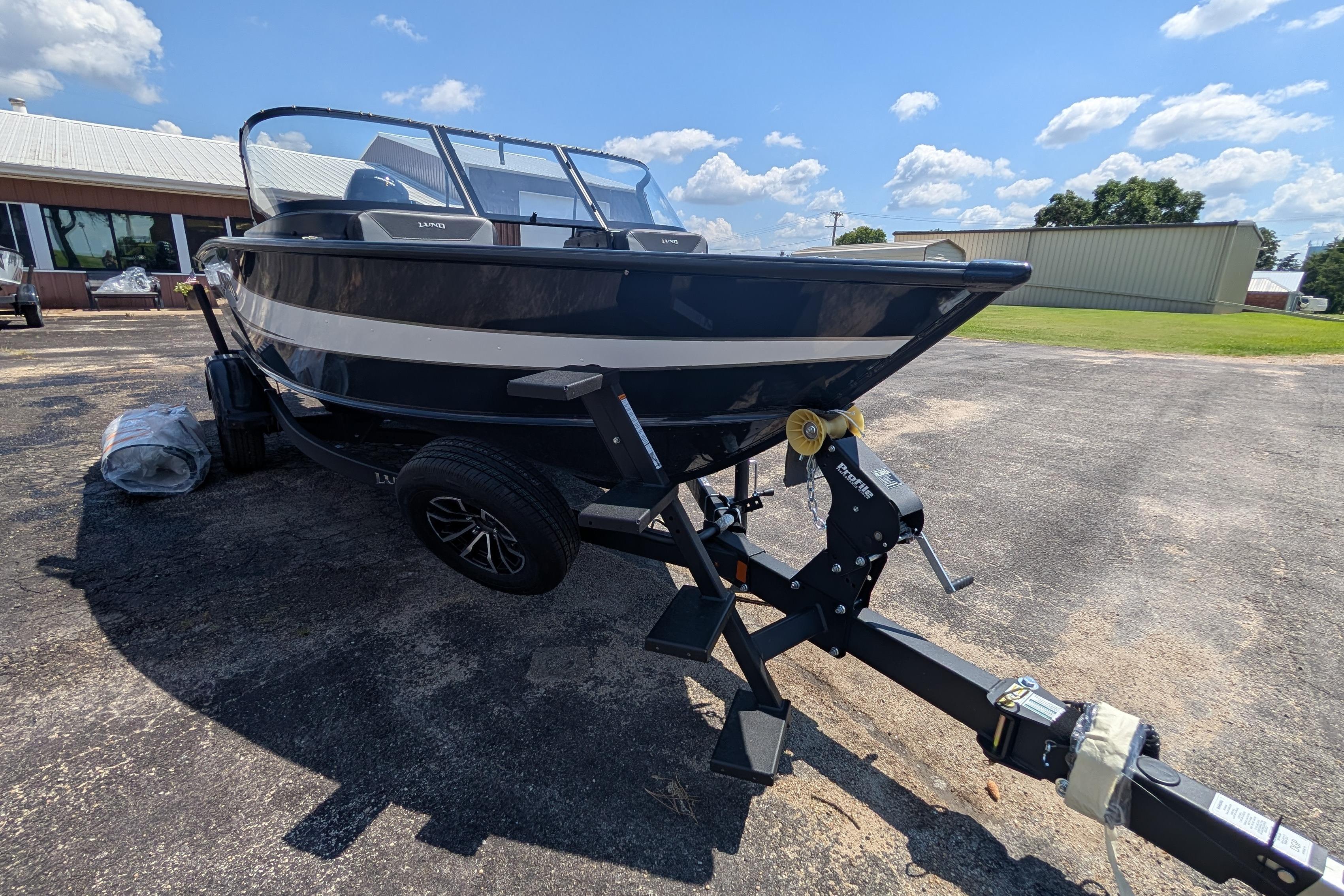 2026 Lund 1875 Crossover XS boat on trailer, parked outdoors under a clear sky.