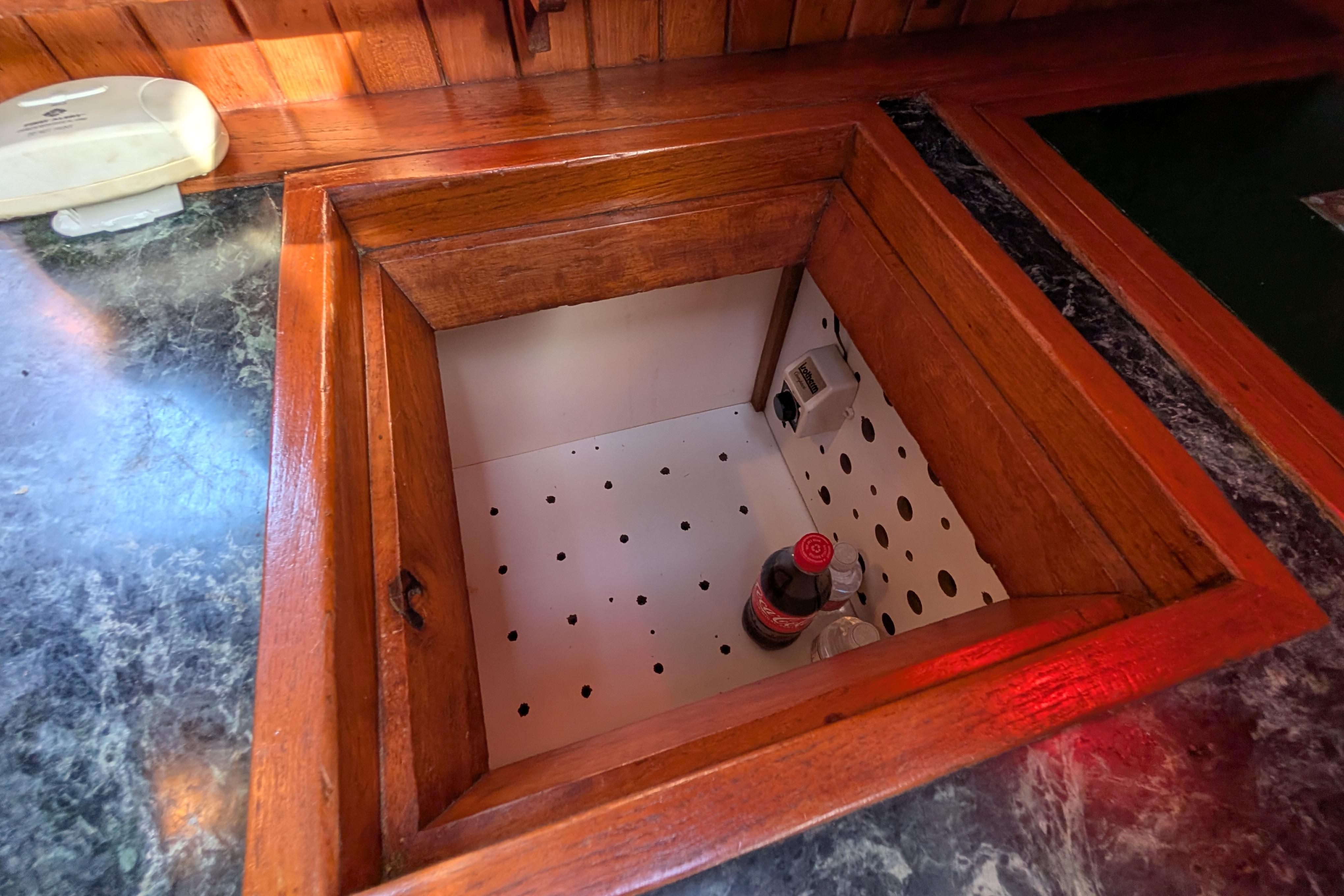 Wooden storage compartment on a 1983 Robert Perry 41 yacht, containing drinks.