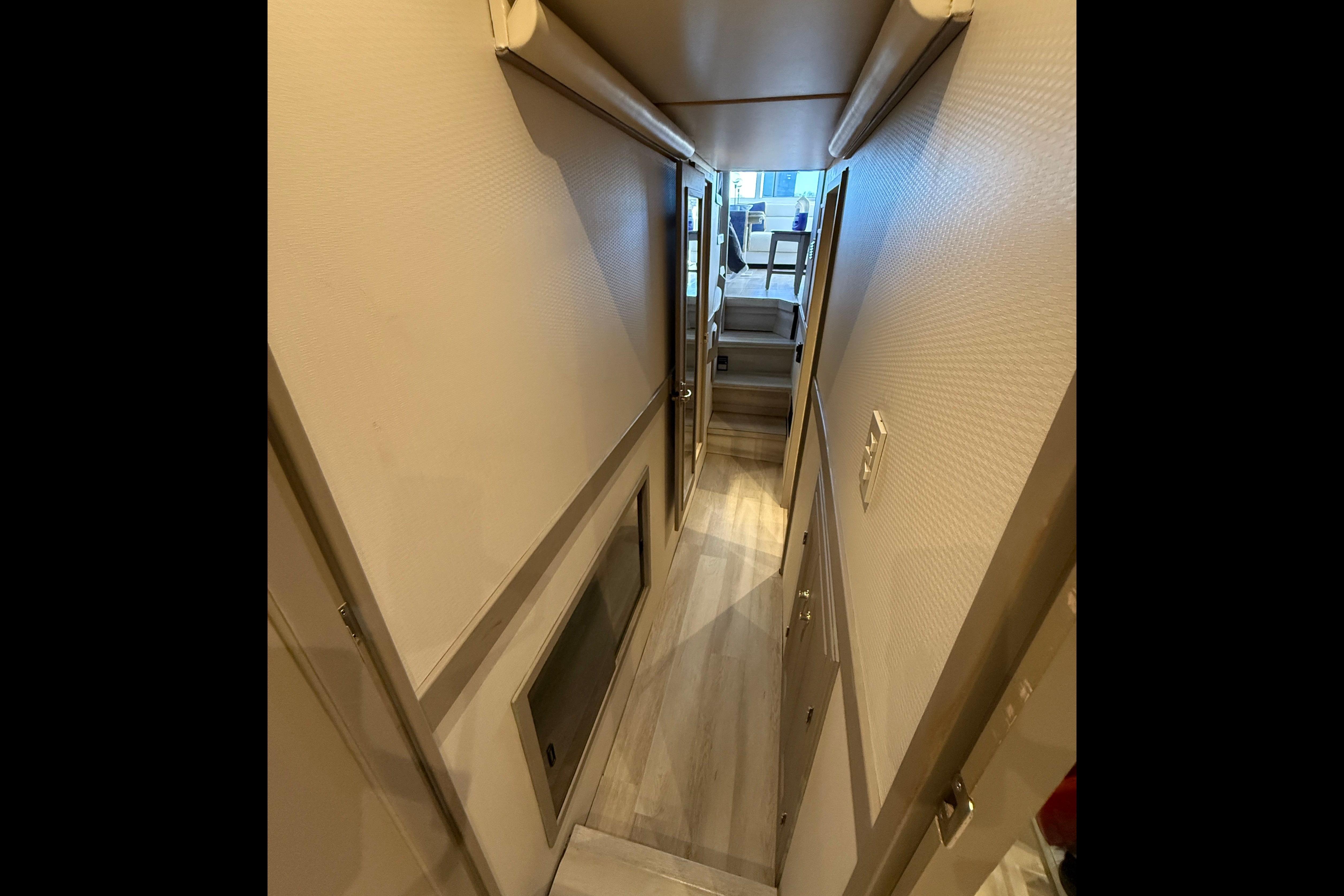 Narrow hallway inside 1997 Bayliner 4788 Pilot House Motoryacht, featuring wooden flooring and doors.