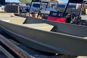 2026 Tracker Grizzly 14 Jon boat displayed outdoors, surrounded by various vehicles.