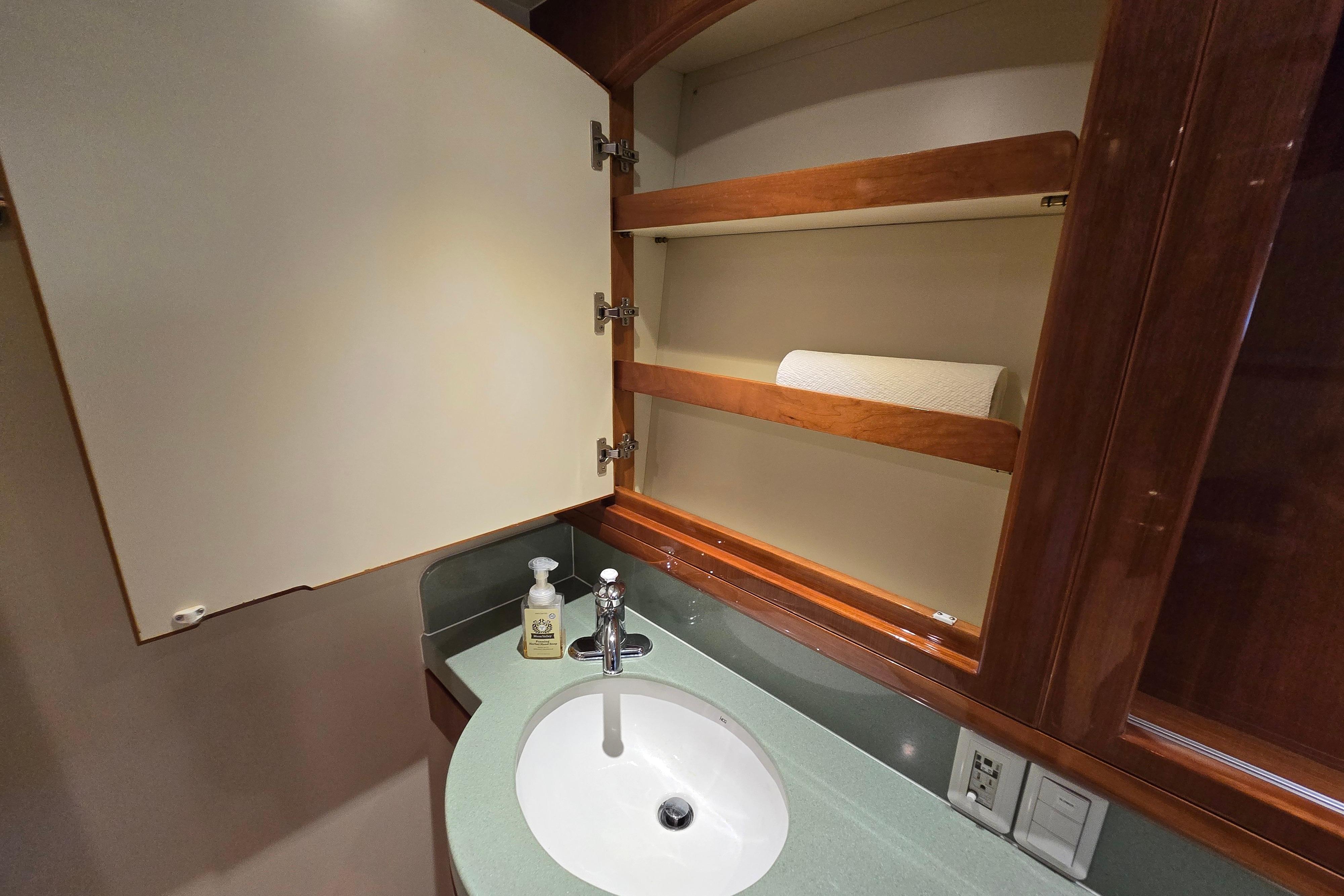 Luxury yacht bathroom with open cabinet, sink, and soap dispenser, Grand Harbour 58, 2004 model.