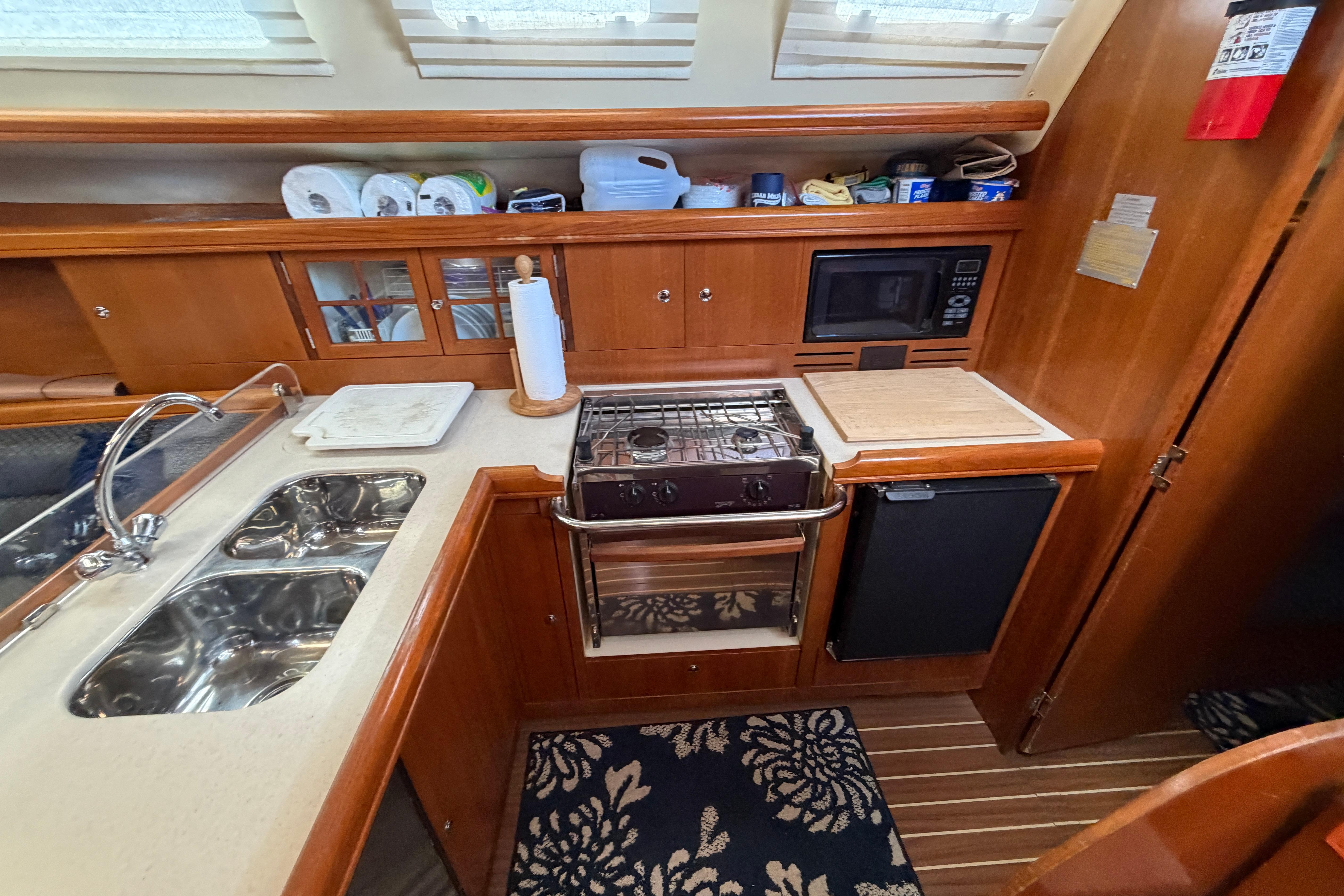 Galley kitchen in 2005 Hunter 38 sailboat with stove, sink, and microwave.