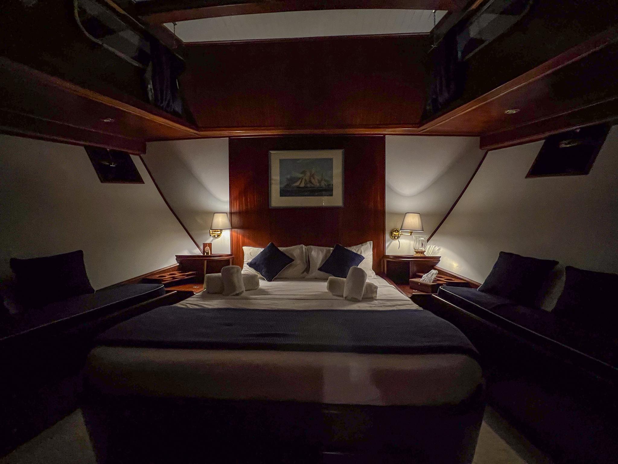 Luxurious cabin interior of a 1969 Psarros Shipyard yacht, featuring elegant bedding and warm lighting.