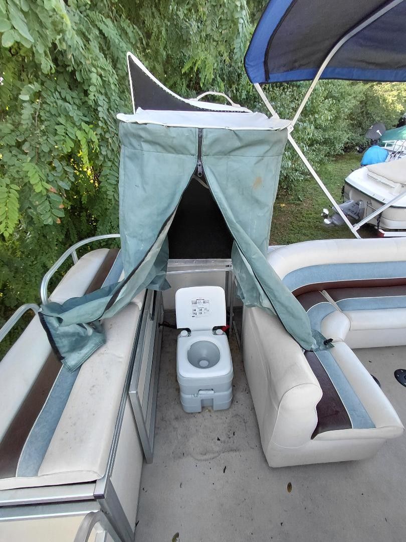 A portable toilet system on a boat with seating and a blue curtain.