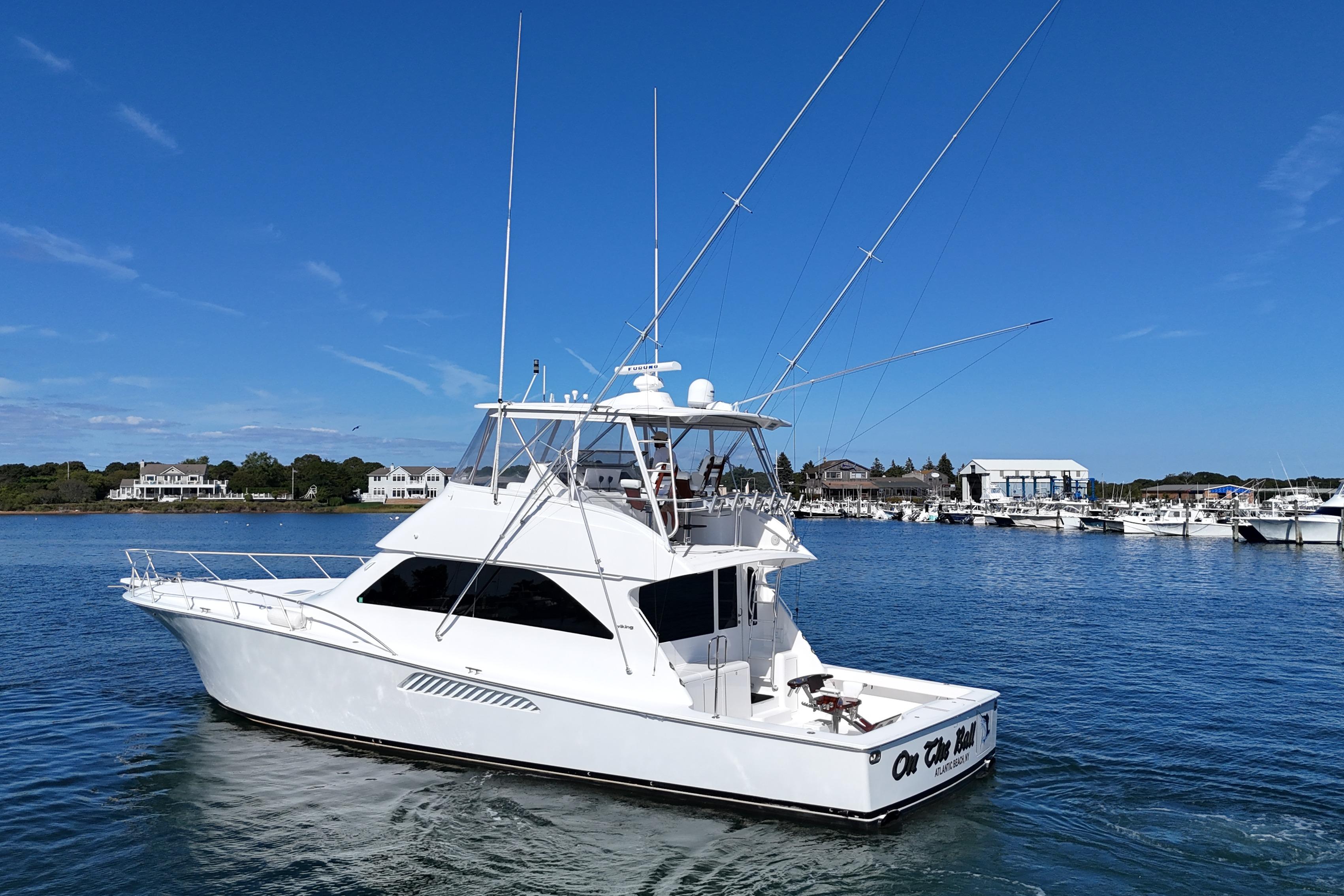 2006 Viking 56 Convertible yacht cruising in a scenic marina under a clear blue sky.