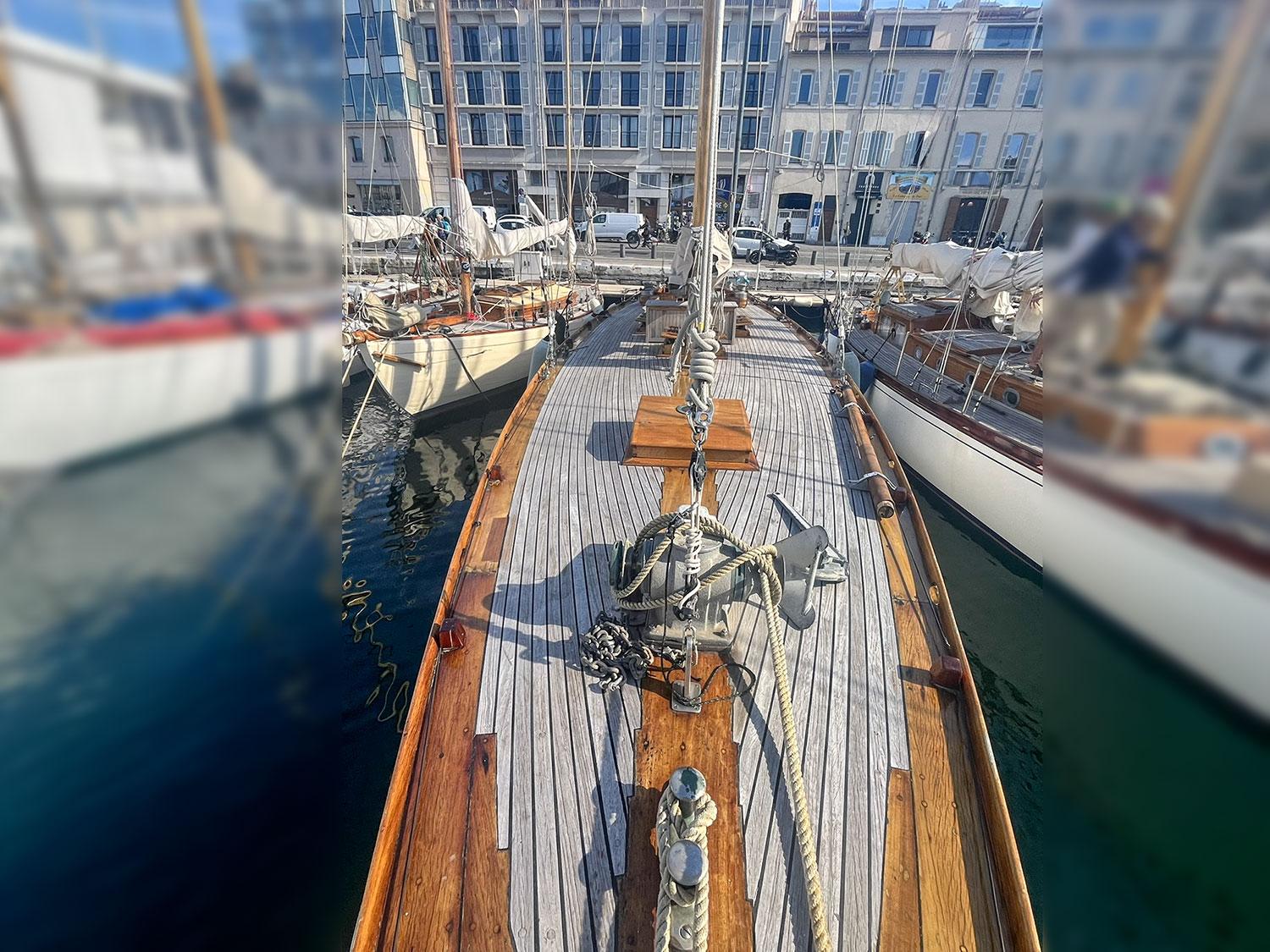 Vintage 1931 Bonin SLOOP sailboat docked in a marina, showcasing classic wooden deck design.