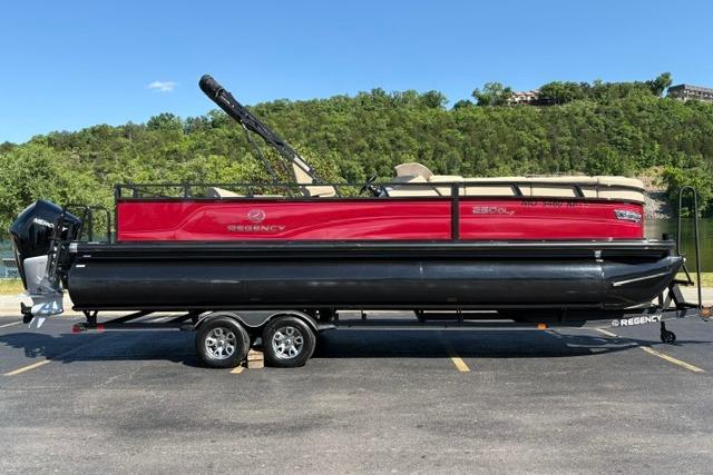 2025 Regency 250 DL3 pontoon boat on trailer, parked outdoors with scenic background.