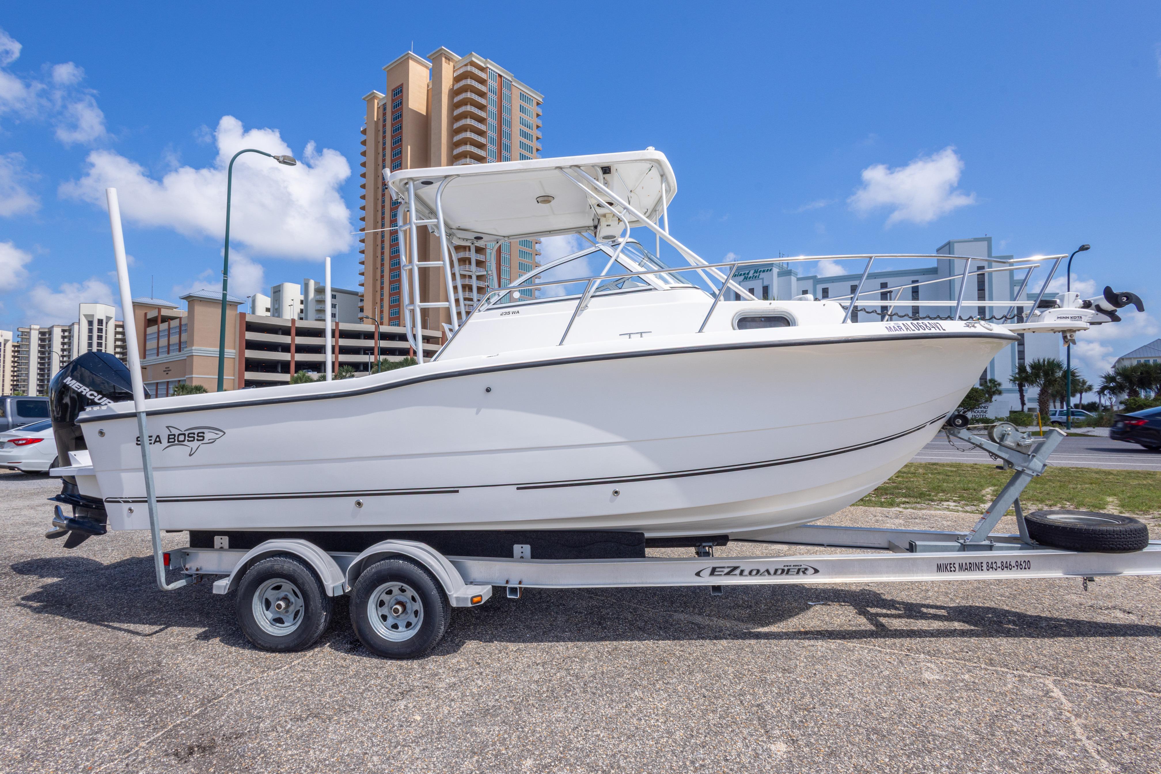 2007 Sea Boss 235 Walkaround boat on trailer, urban background, clear sky.