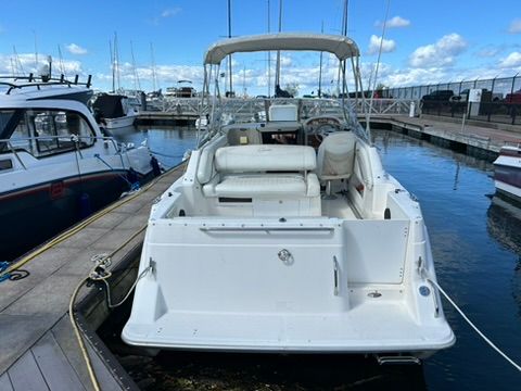 A 1997 Bayliner 2566 Ciera docked. It features an open cockpit and a canopy.
