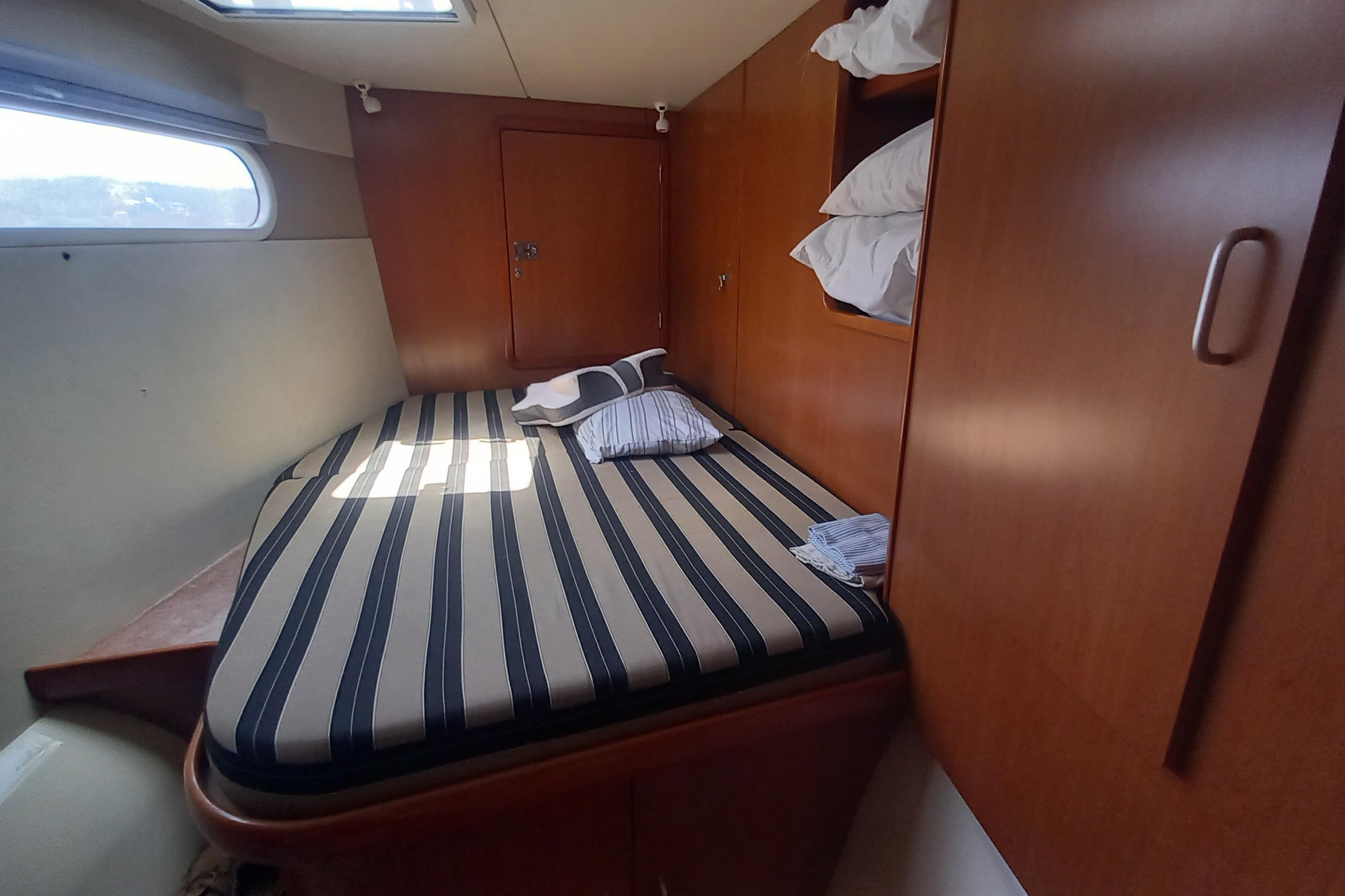 Cozy cabin interior of 2010 Leopard 46 yacht with striped bedding and wooden storage.