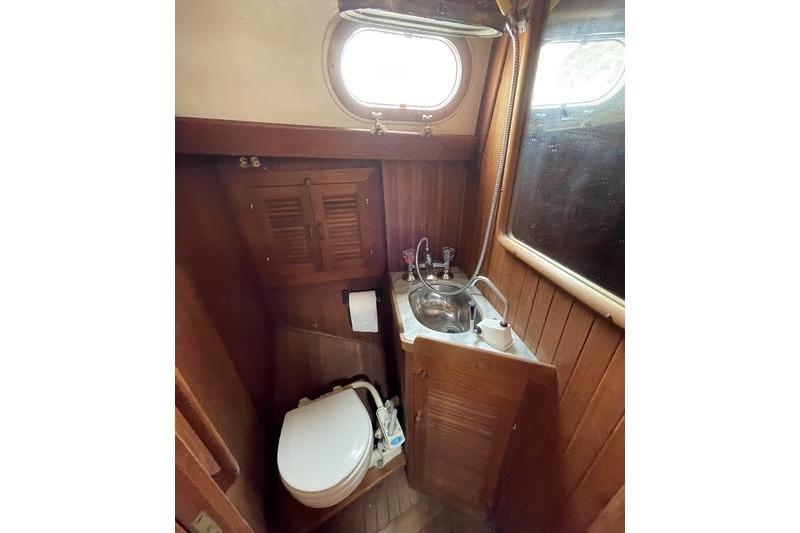 Compact bathroom in 1980 Ta Shing Baba 30 sailboat with wooden interior and porthole window.
