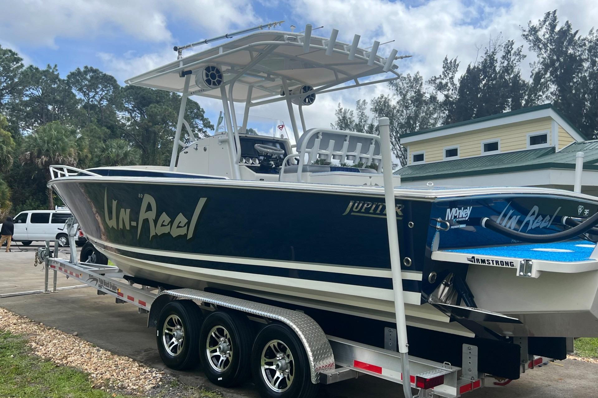 2004 Jupiter 31 Cuddy boat on trailer, featuring "Un-Reel" branding, parked outdoors.