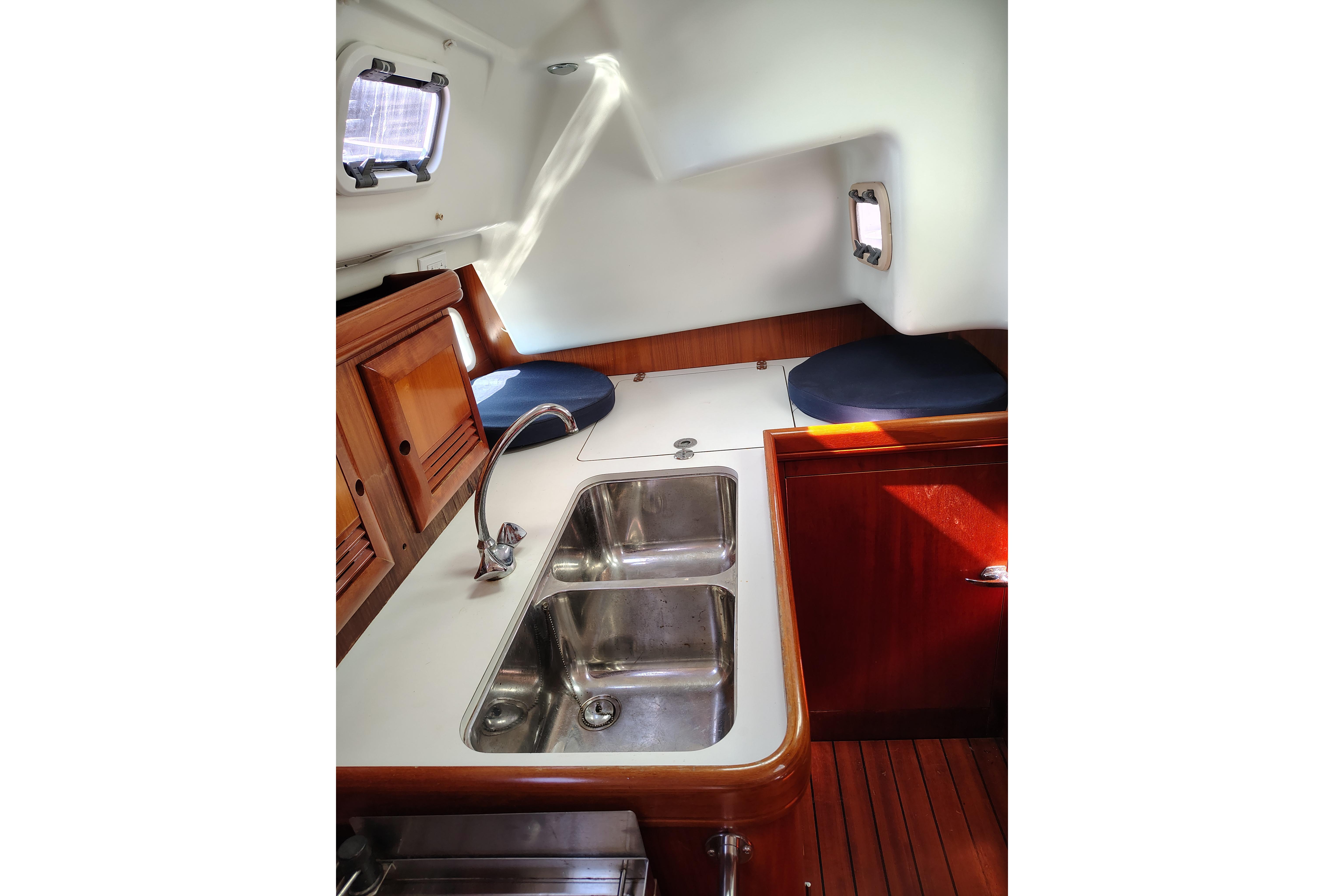 Interior of 2001 Beneteau Oceanis 411 yacht with sink and wooden cabinetry.