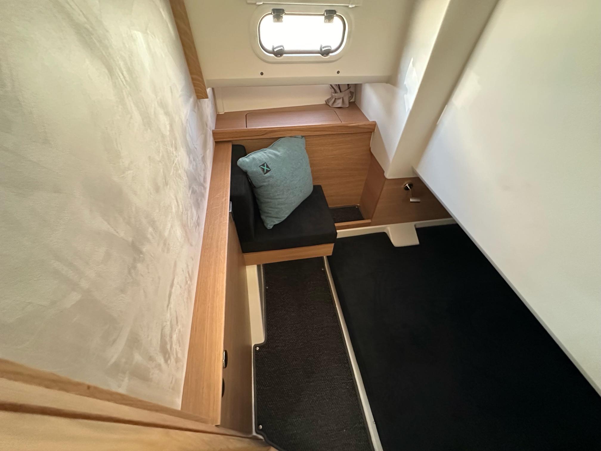 2023 Nimbus T11 cabin interior with wooden accents, black seating, and a small window.