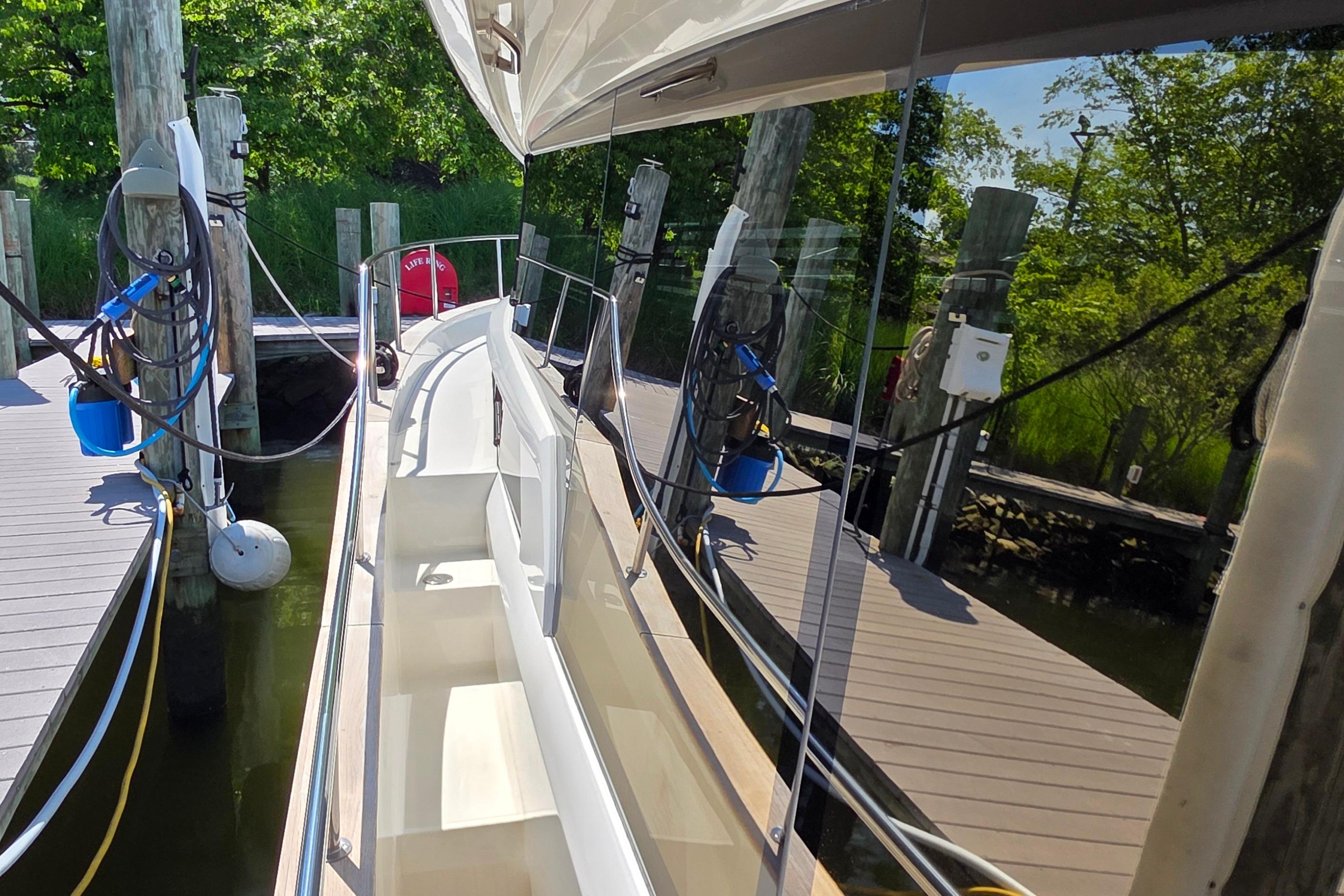 2023 Greenline 40 yacht docked, reflecting lush greenery and marina surroundings.
