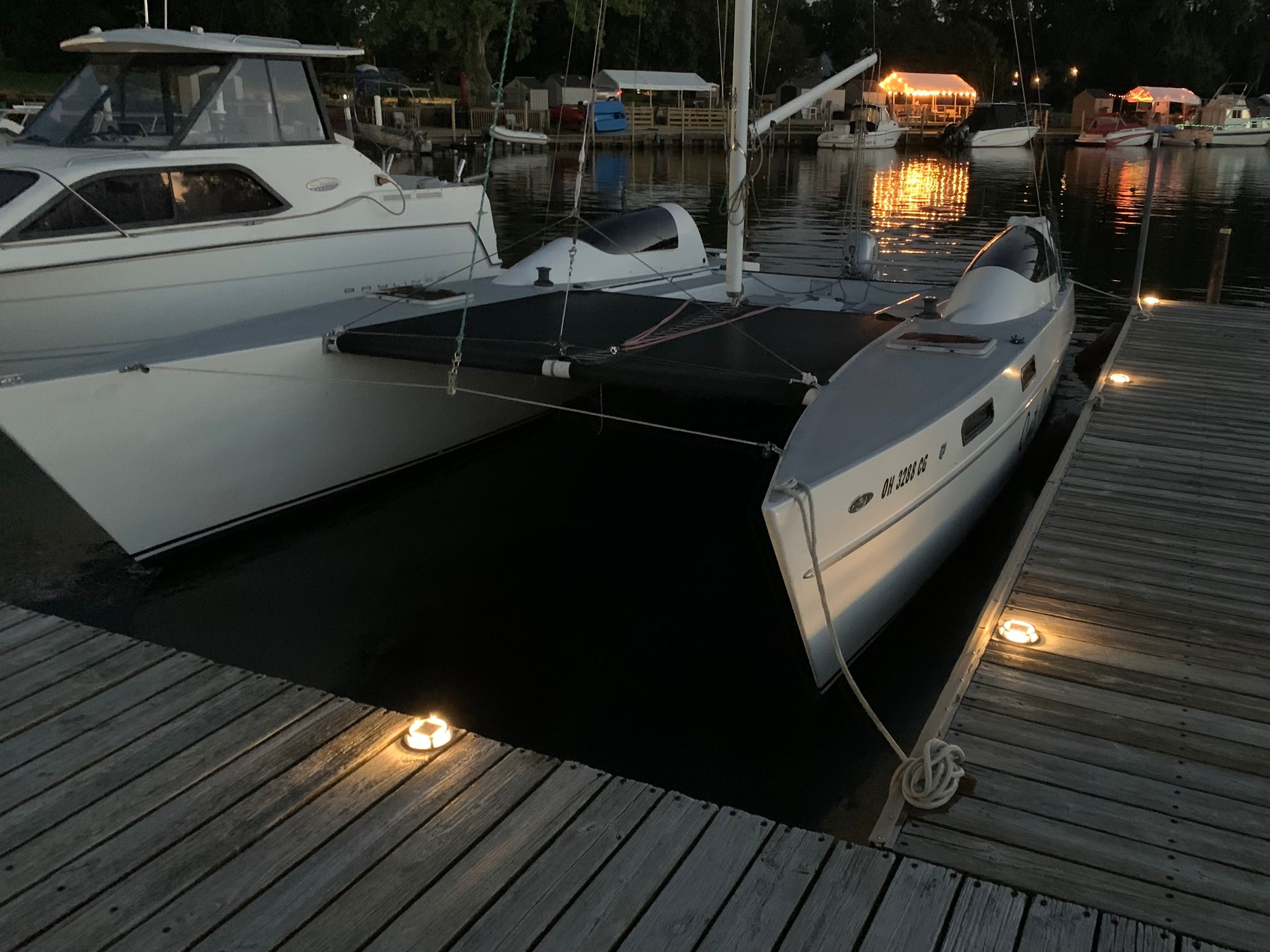 Catamaran docked at sunset, surrounded by other boats.