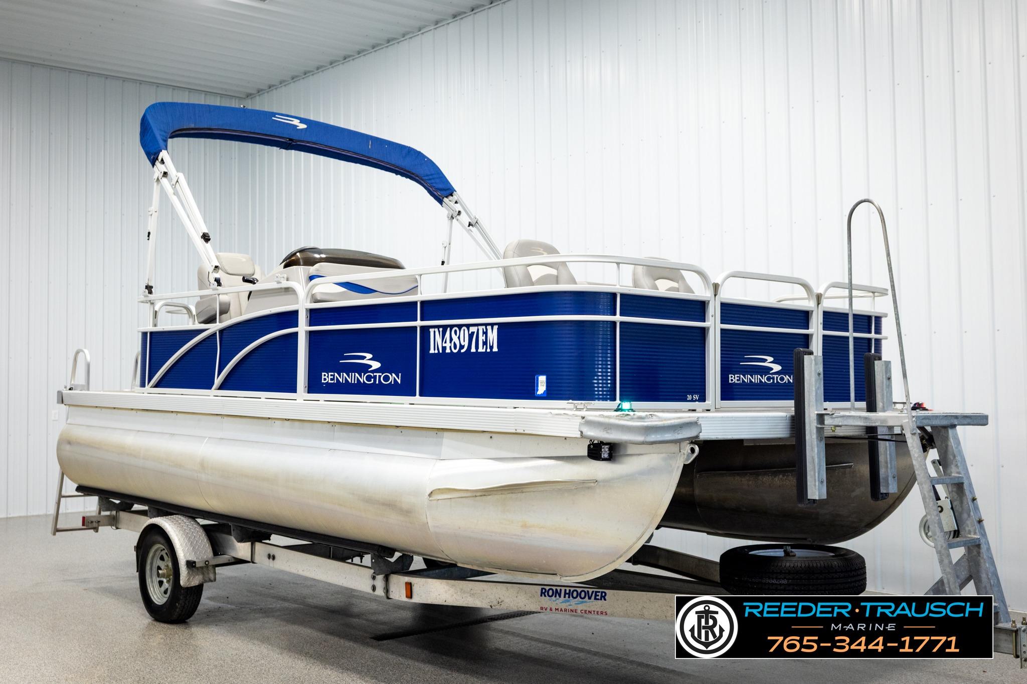 2021 Bennington 20 SV pontoon boat with blue canopy on trailer in indoor showroom.