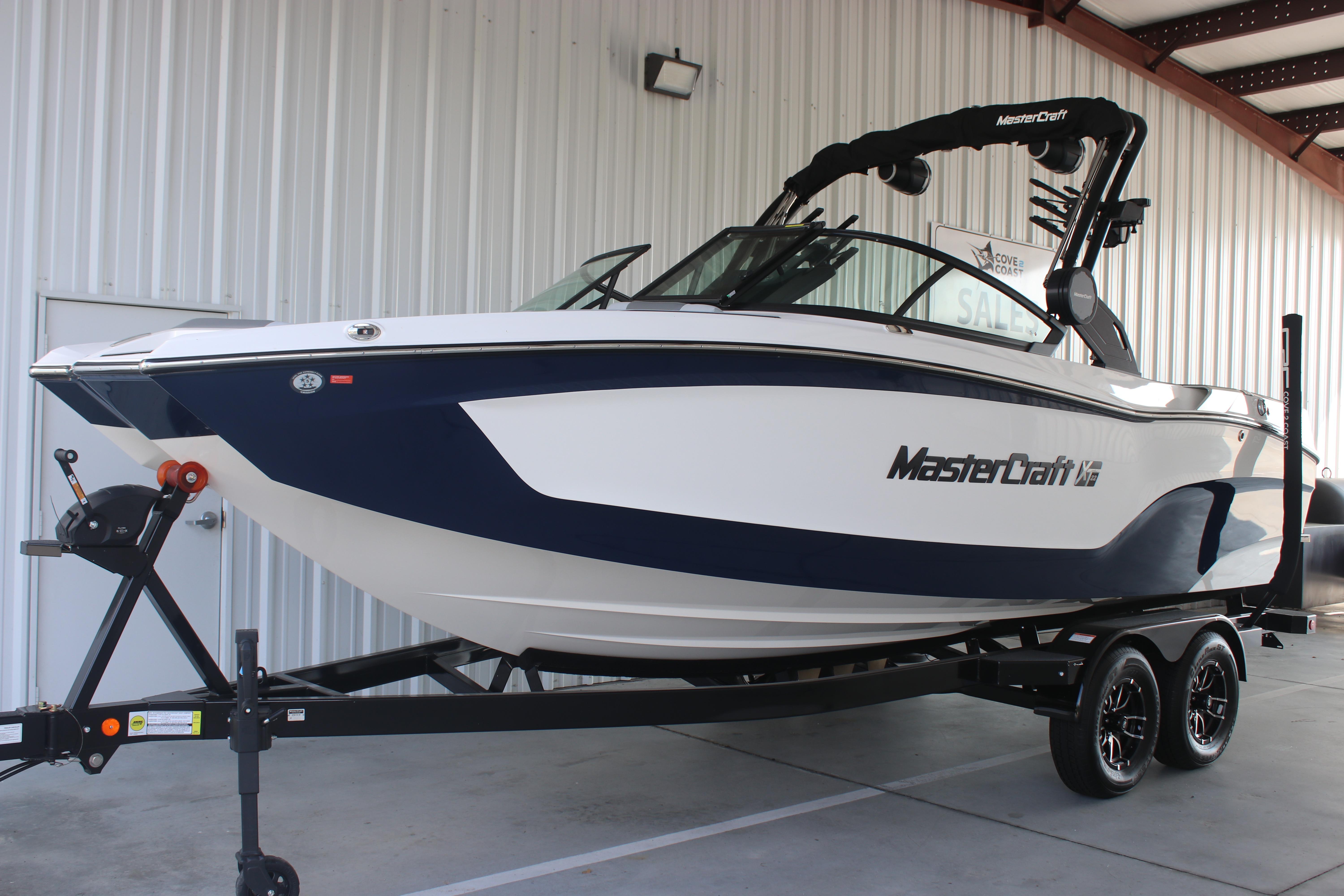 2025 MasterCraft XT22 boat on trailer, displayed in a showroom setting.