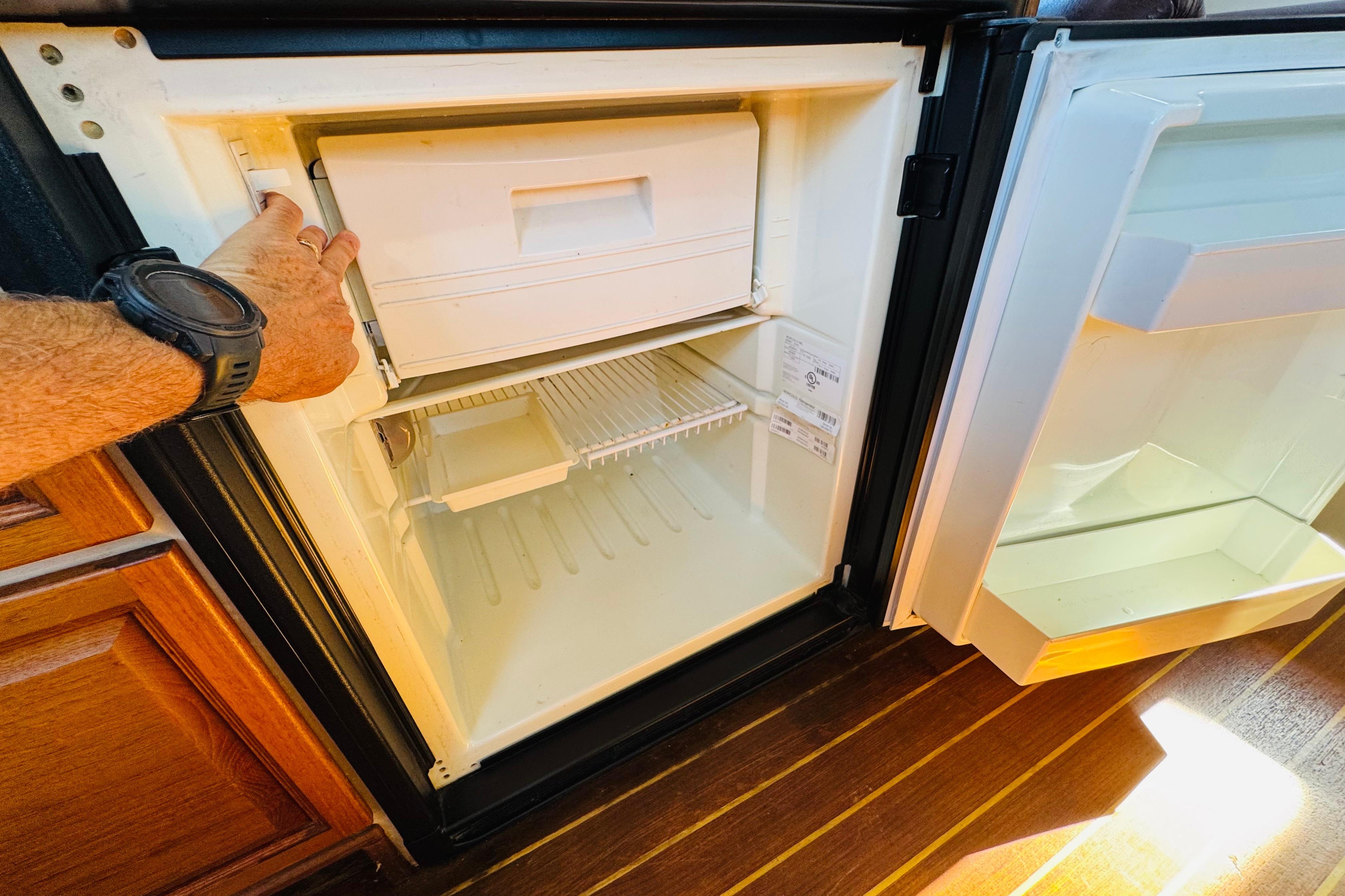 Open refrigerator on a 1996 Nordic Tug 32 boat, showing interior shelves and freezer compartment.