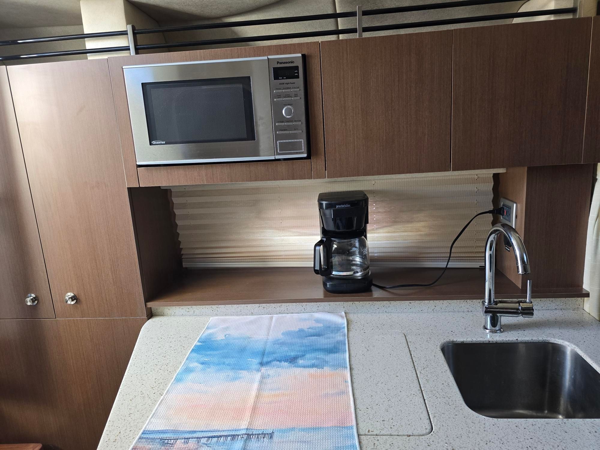 Interior of a yacht kitchen with microwave, coffee maker, and sink.