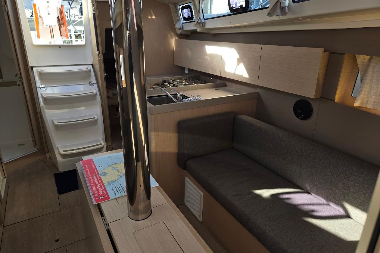 Interior of 2023 Beneteau Oceanis 38.1 yacht, featuring modern kitchen and seating area.