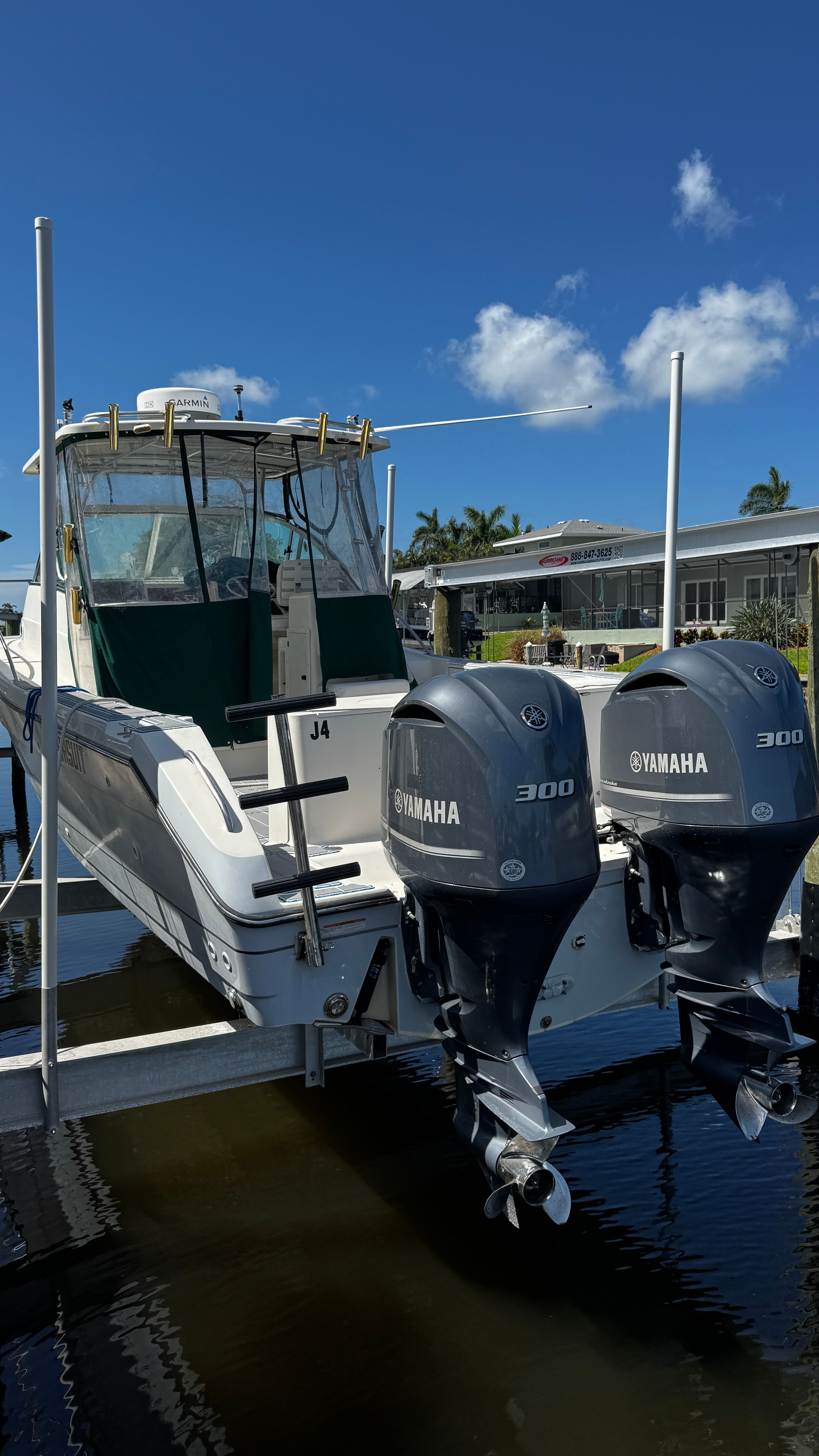 2003 Pursuit 3070 with twin Yamaha engines, on a boat lift above the water.