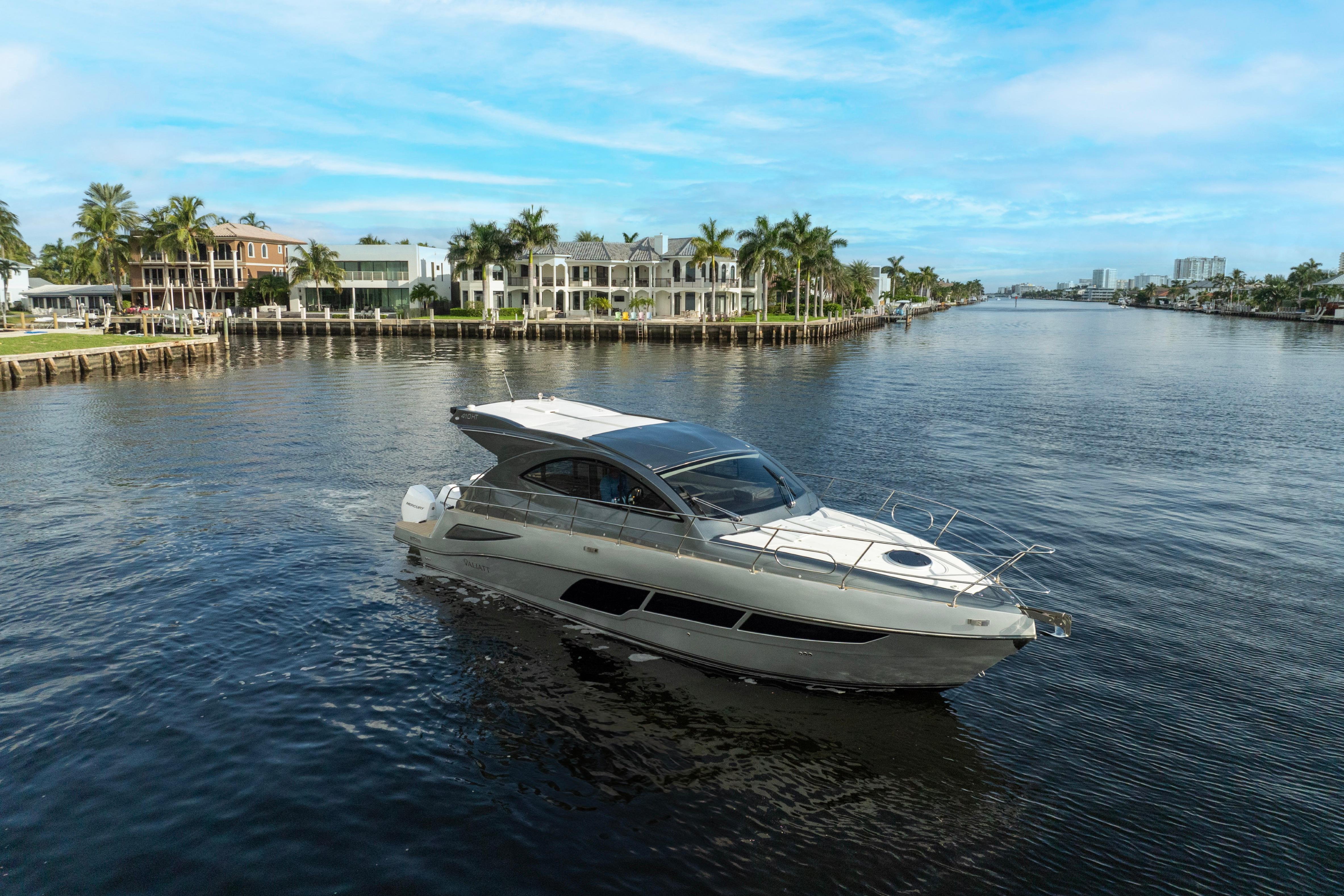 2025 Valiatt 410HT yacht cruising on a scenic waterway with luxury homes in the background.