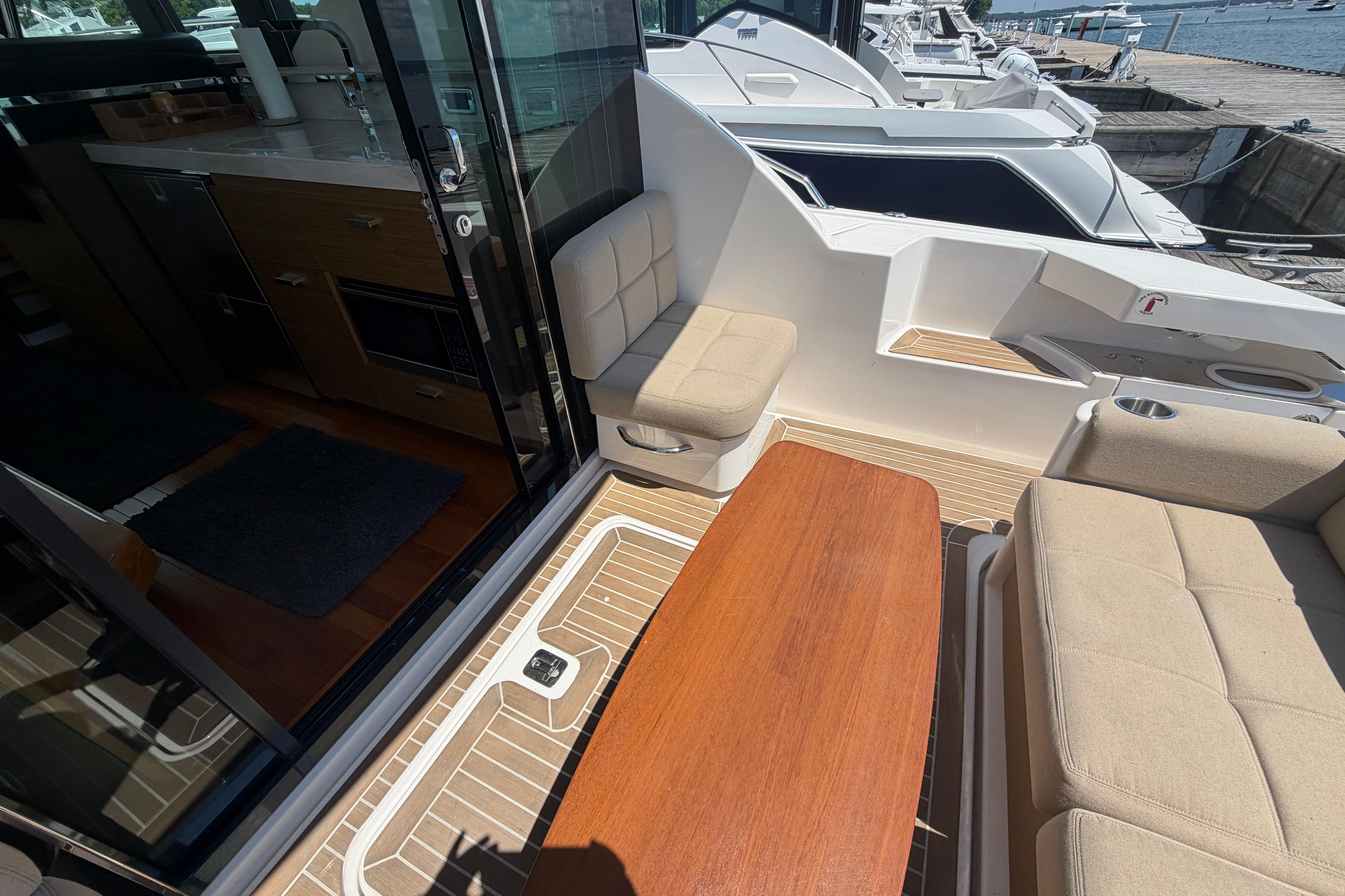 2016 Tiara Yachts C39 Coupe interior with seating and wooden table, docked at marina.